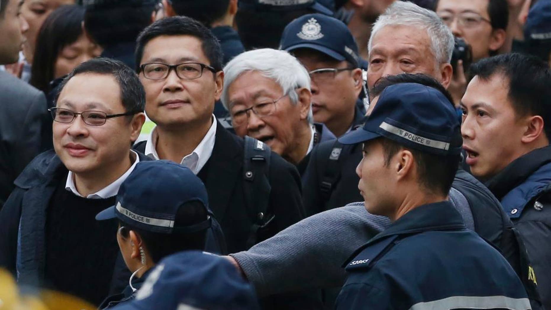 Four protest leaders, from left, Benny Tai Yiu-ting, Chan Kin-man, Joseph Zen and Chu Yiu-ming, surrounded by police officers, walk to the police station in Hong Kong as they surrender to police Wednesday, Dec. 3, 2014 to take responsibility for protests that have shut down parts of the Asian financial center for more than two months. Three founders of Hong Kong's pro-democracy protest movement called for an end to street demonstrations to prevent more violence and take the campaign to a new stage, but it wasn't clear whether student protesters, who make up the bulk of the activists, would heed the call. (AP Photo/Kin Cheung)