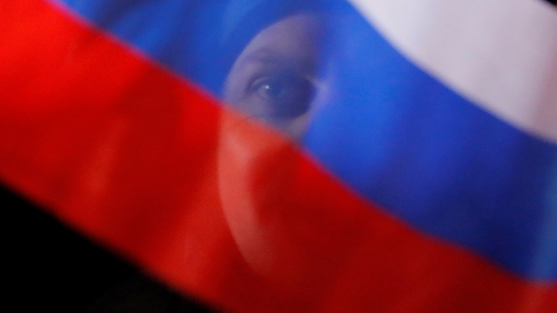 A man waves Russian flag during a rally and concert marking the fourth anniversary of Russia's annexation of the Crimea region, at Manezhnaya Square in central Moscow, Russia March 18, 2018. REUTERS/Maxim Shemetov