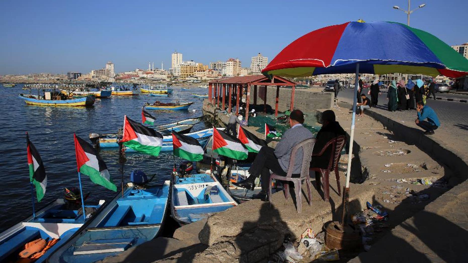 File - In this Sunday, April 17, 2016 file photo, Palestinians protect themselves from the sun at the fishermen port in Gaza City. Israel's transportation minister Yisrael Katz said he is pushing for the construction of an "artificial island" off the coast of Hamas-ruled Gaza to alleviate hardship in the blockaded coastal strip.With Israel and Egypt maintaining a naval blockade of Gaza, the Palestinians have long been pleading for a port to connect them to the rest of the world. (AP Photo/Adel Hana, File)