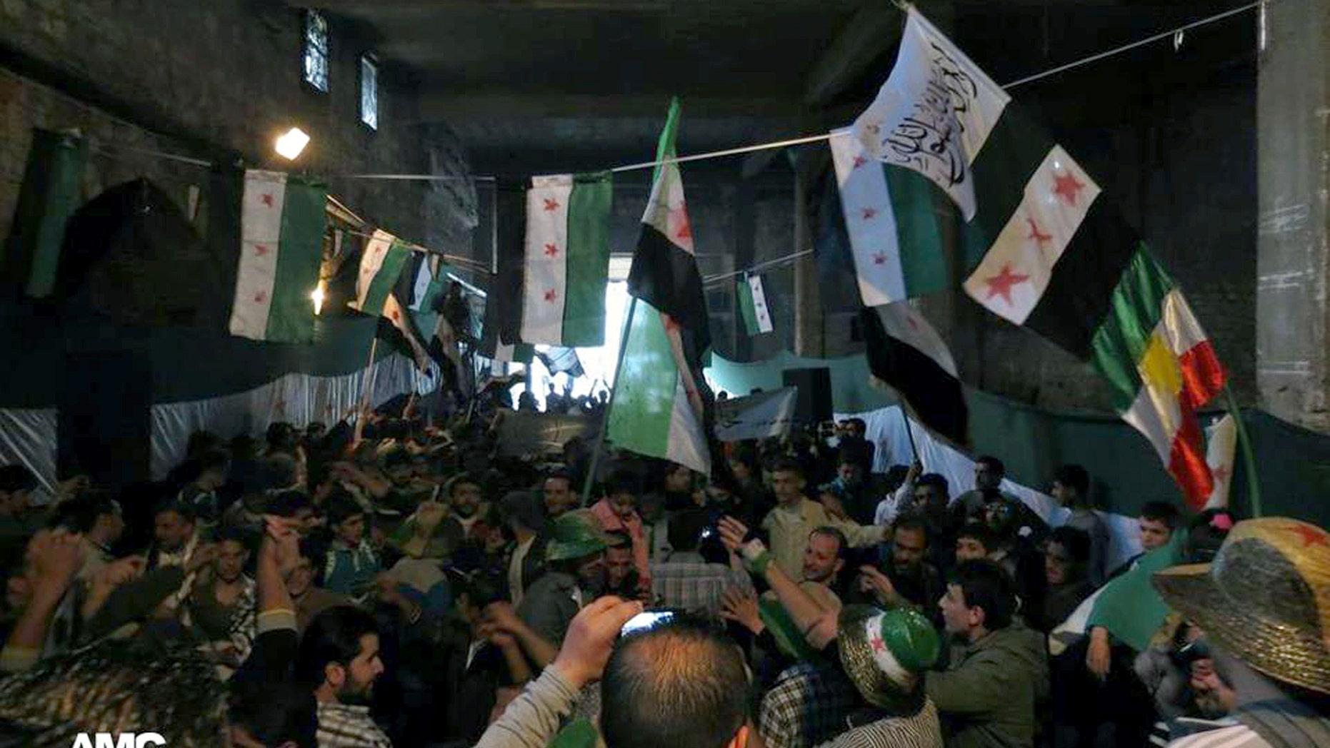 This citizen journalism image provided by Aleppo Media Center AMC which has been authenticated based on its contents and other AP reporting, shows anti-Syrian regime protesters holding Syrian revolution flags, during a rally marking the anniversary of the 1946 withdrawal of French troops from Syria, which marked the end of France's mandate of the Arab country, in the old quarter of the northern city of Aleppo, Syria, Wednesday, April 17, 2013. (AP Photo/Aleppo Media Center AMC)