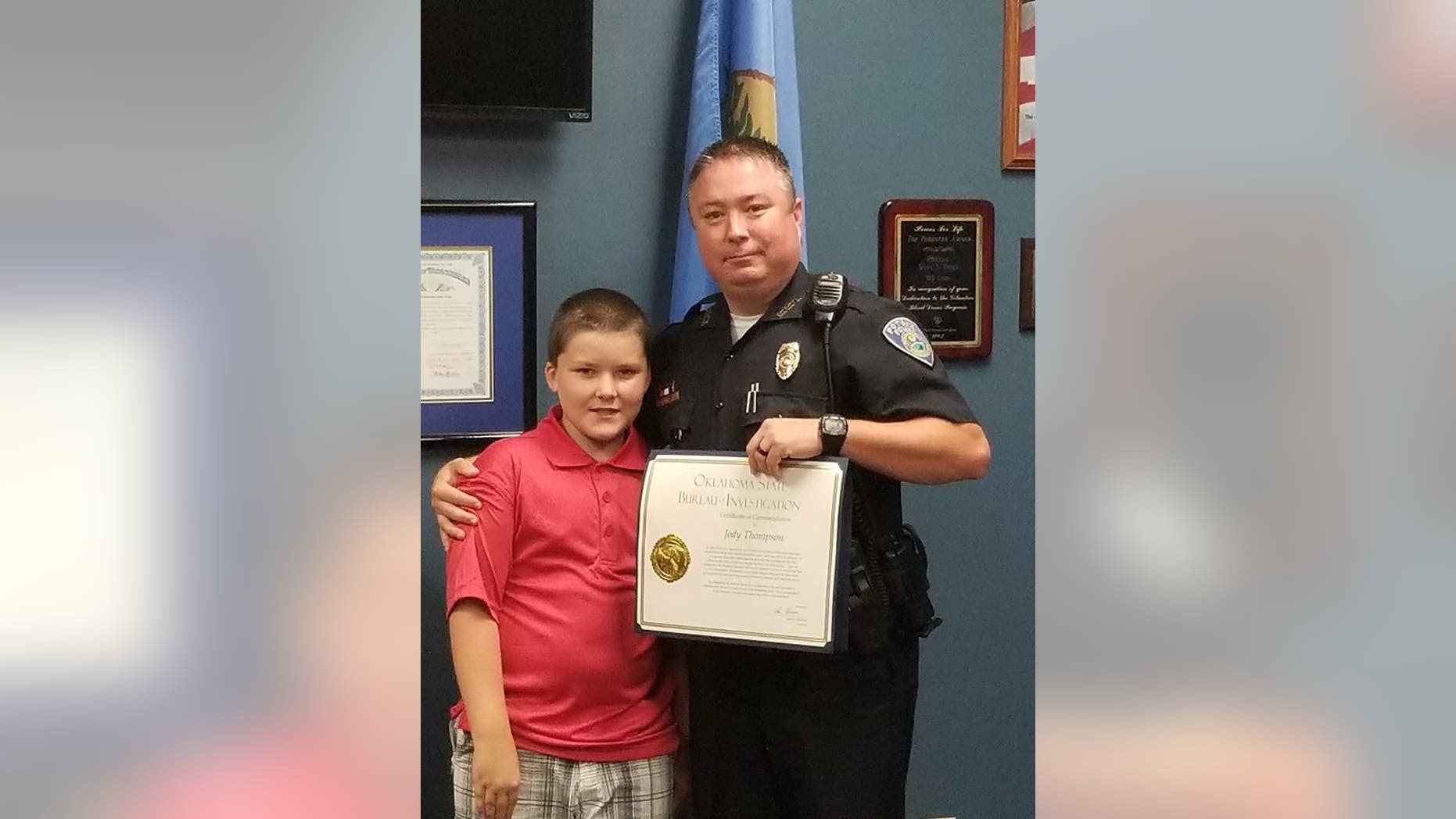 Officer Jody Thompson after receiving his certificate of commendation, posing with John.