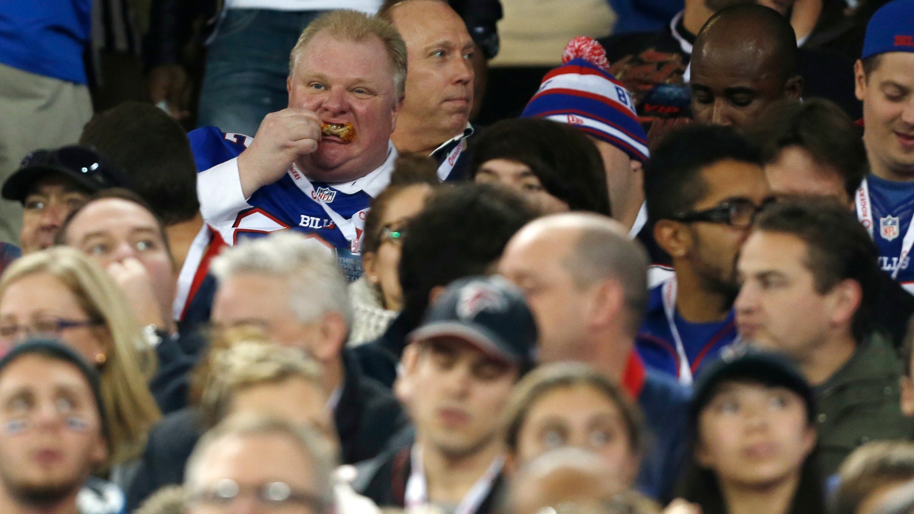 Toronto Mayor Rob Ford eats during the first half of an NFL football game between the Atlanta Falcons and the Buffalo Bills on Sunday, Dec. 1, 2013, in Toronto. (AP Photo/Gary Wiepert)