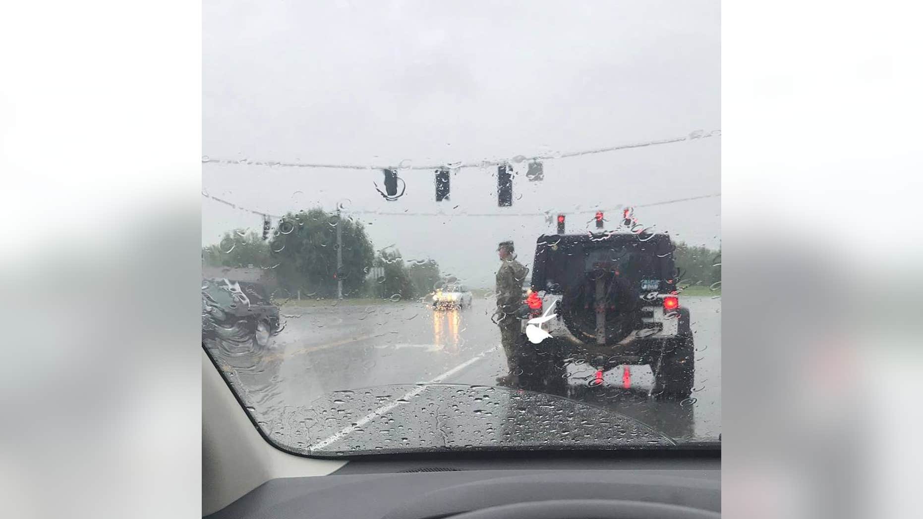 A soldier got out of his car to salute a funeral procession in the rain.