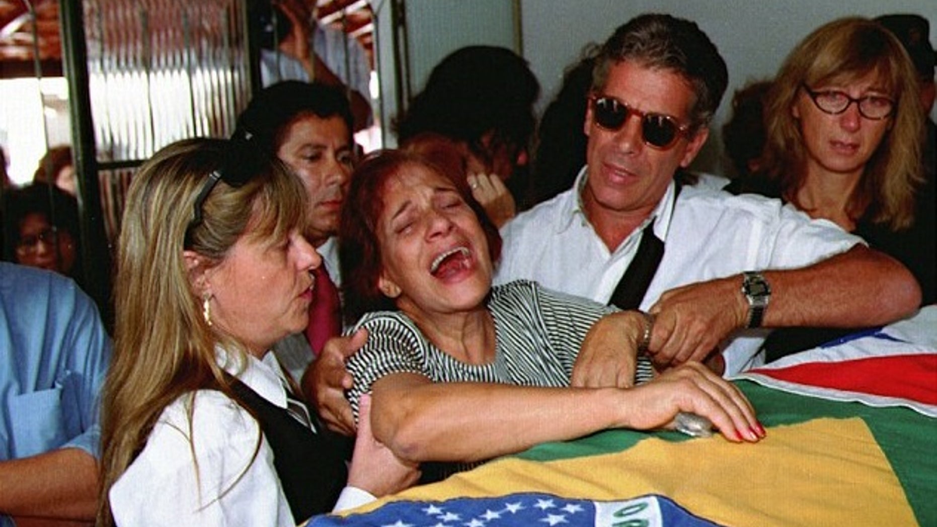 Lidia Pinto Machado, center, mother of Maria Isabel Monteiro Alves, mourns over her daughter's coffin during funeral services in 1995.