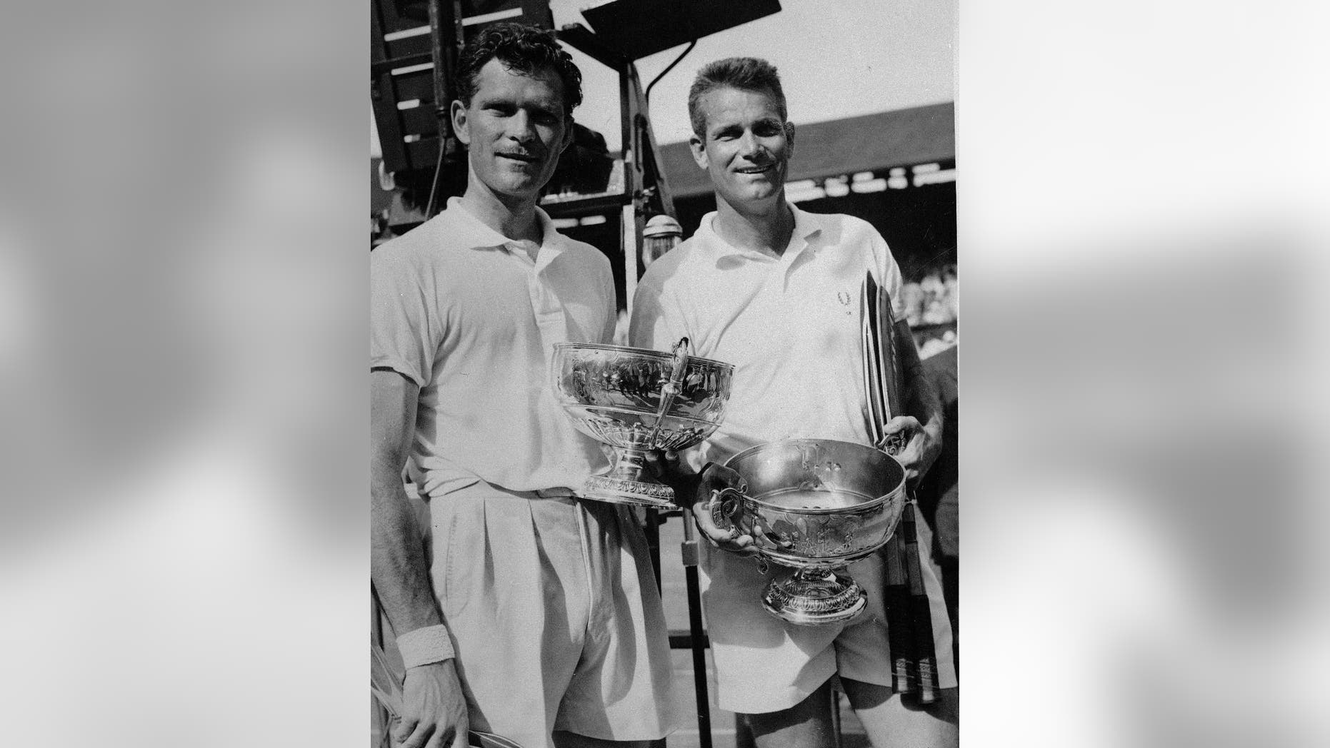 FILE - In this July, 6, 1957, file photo, winning doubles partners Budge Patty, left, and Gardnar Mulloy, both of the United States, hold their trophies after being presented by Queen Elizabeth at Wimbledon. Mulloy, a member of the International Tennis Hall of Fame who won 129 U.S. national titles, died Monday night, Nov. 14, 2016, in Miami. He was 102. (AP Photo/File)