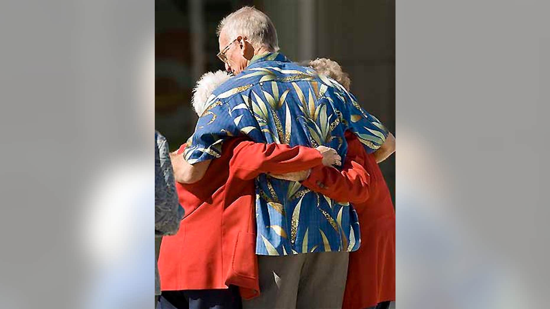 Two red-coated ushers at televangelist Robert H. Schuller's Crystal Catherdral get a hug after witnessing a man shoot himself in the church.