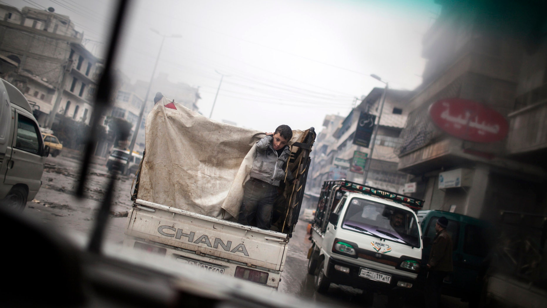 A boy is seen through a car window as he rides on the back of a truck in the streets of Aleppo, Syria, Saturday, Jan. 5, 2013. The revolt against President Bashar Assad that started in March 2011 began with peaceful protests but morphed into a civil war that has killed more than 60,000 people, according to a recent United Nations recent estimate. (AP Photo/ Andoni Lubaki)