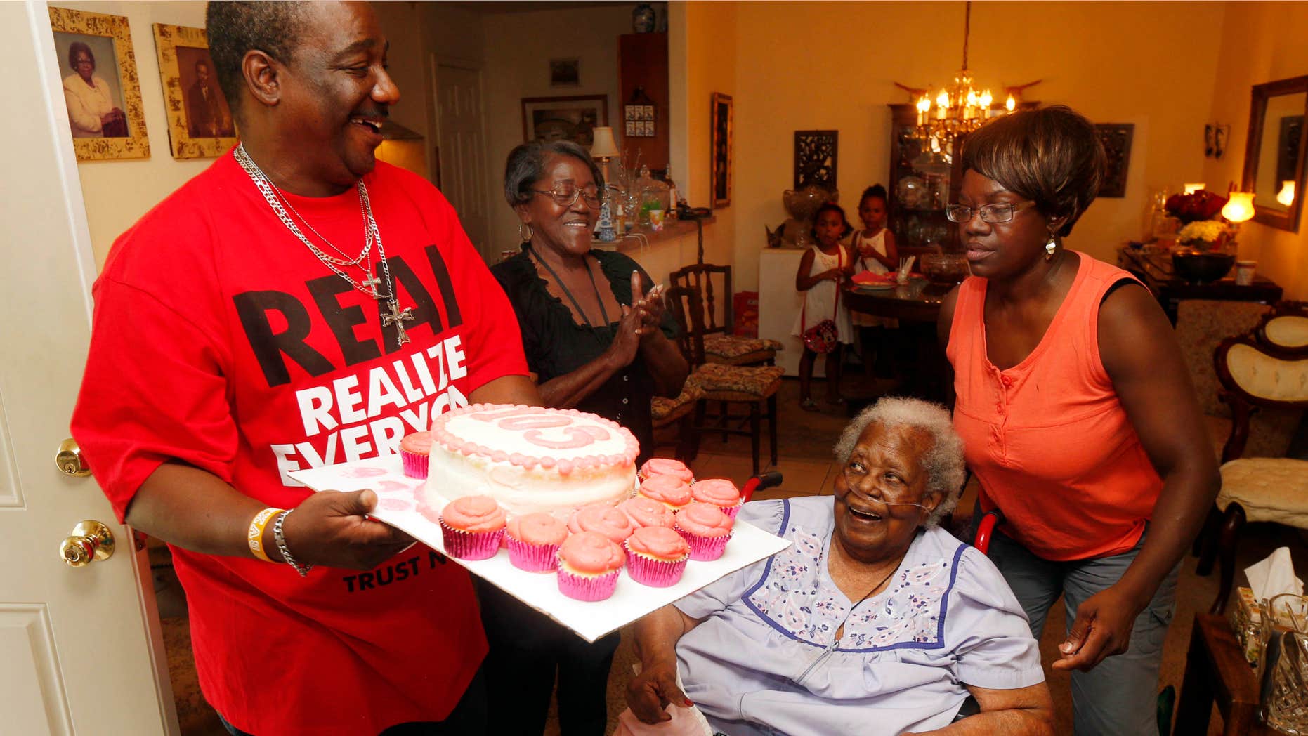 FILE- In this July 25, 2015, file photo, Terrance Jackson, left, Doris Ware, second from left, and Beverly Booker, right, sing "Happy Birthday To You" to Bernice Williams, seated, as she celebrates her 103rd birthday in the Mill City neighborhood of Dallas.
