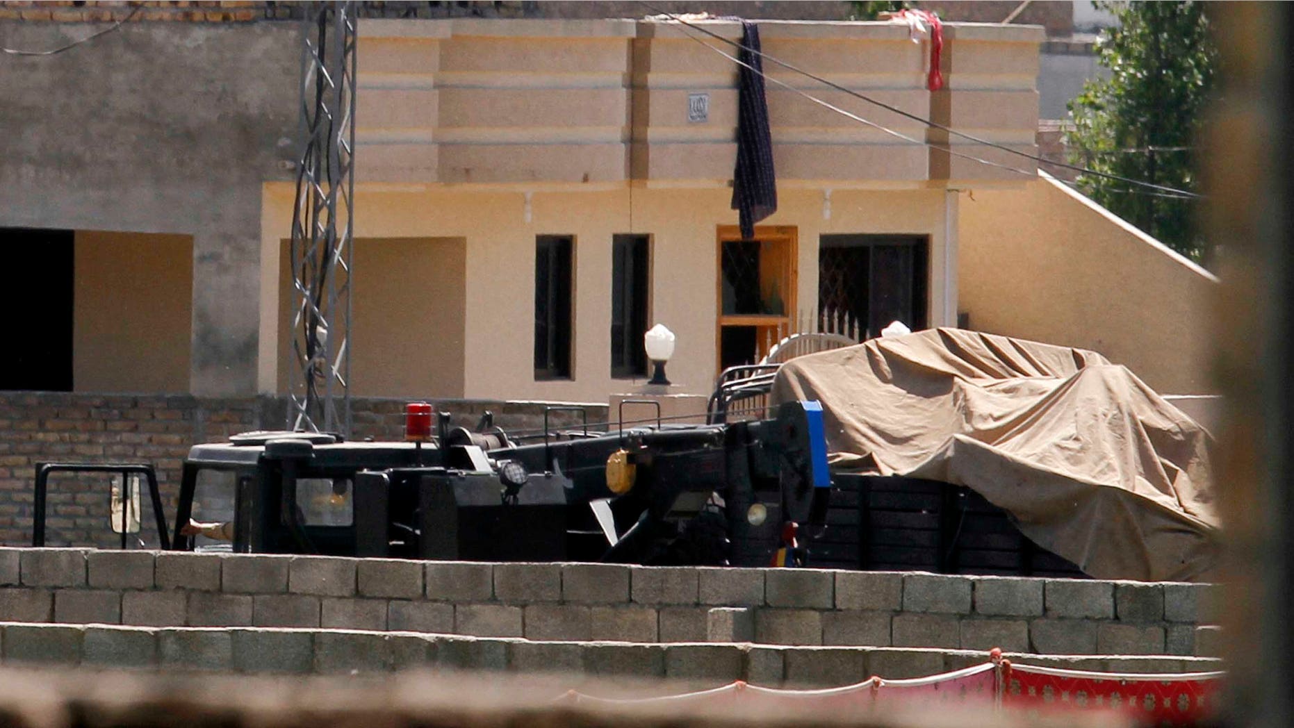 Vehicles are parked inside the compound of a house where it is believed al-Qaida leader Osama bin Laden lived in Abbottabad, Pakistan on Monday, May 2, 2011. Bin Laden, the glowering mastermind behind the Sept. 11, 2001, terror attacks that killed thousands of people, was slain in his hideout in Pakistan early Monday in a firefight with U.S. forces, ending a manhunt that spanned a frustrating decade. (AP Photo/Anjum Naveed)
