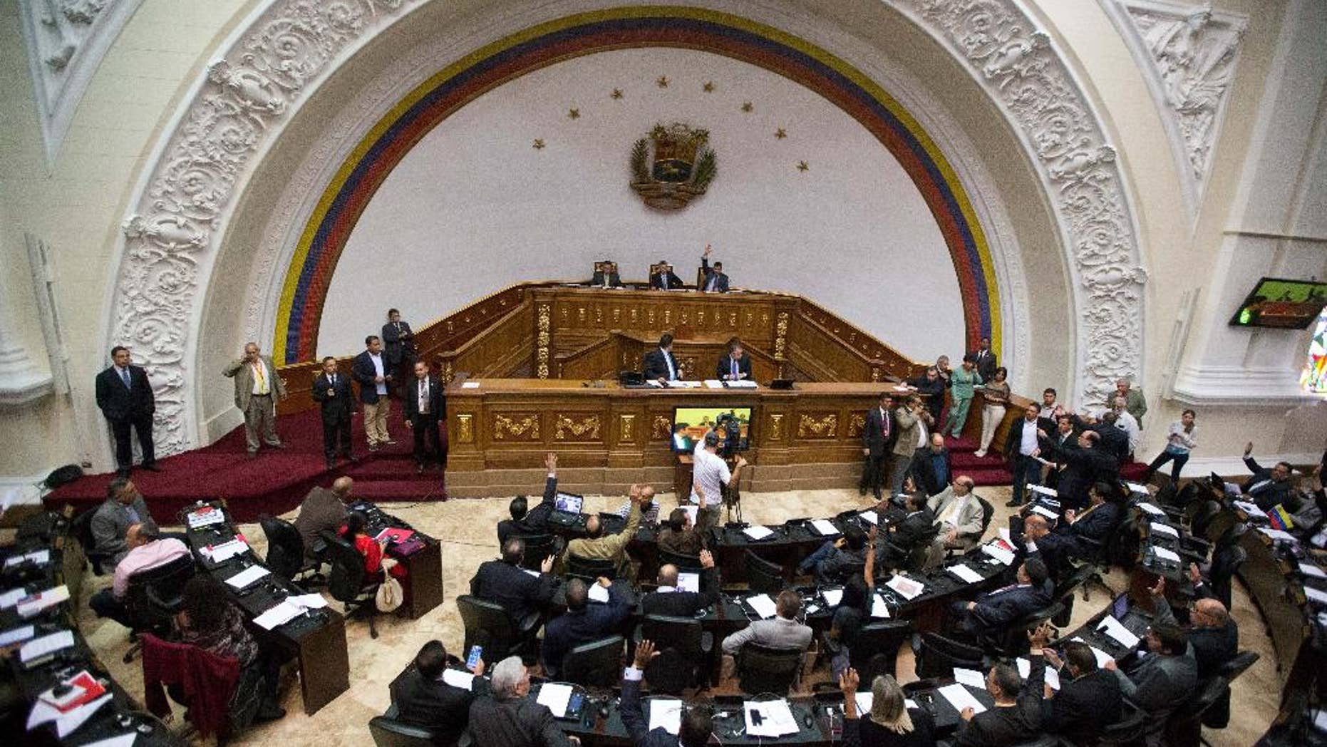 FILE - In this Jan. 6, 2016, file photo, lawmakers vote on the daily agenda during the first National Assembly session in Caracas, Venezuela. The country’s attorney general said Saturday, July 30, that the National Assembly is now illegally constituted because in recent days it swore in three members who’d been ruled out by the government-friendly Supreme Court. (AP Photo/Fernando Llano, File)