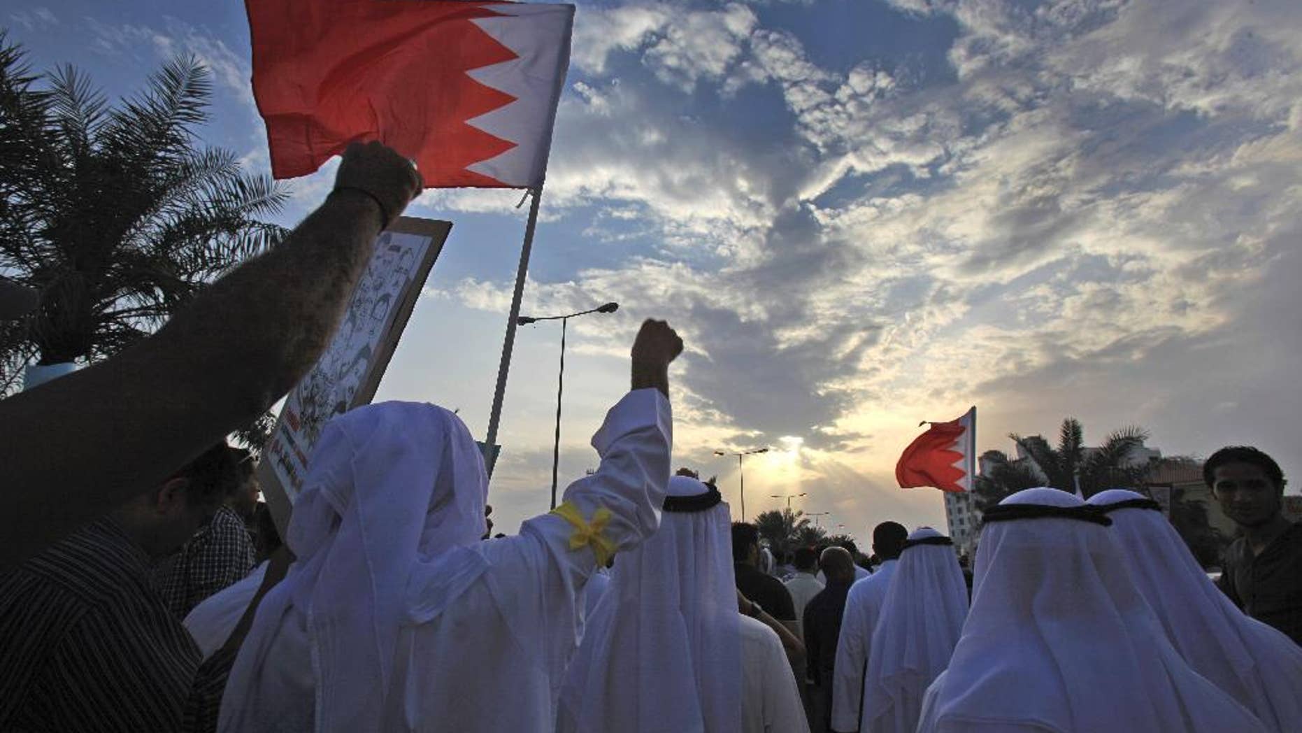 FILE- In this Friday, March 21, 2014 file photo, Bahraini pro-democracy protesters wave signs and pictures of prisoners and people killed in three years of unrest as well as national flags during a march in Abu Saiba, west of the capital of Manama, Bahrain. In Bahrain, people are outraged over the shooting death of a 28-year-old woman in front of her 6-year-old, which activists say was carried out by a royal family member in December 2016. The accusation goes to the heart of lingering unrest on the island off the coast of Saudi Arabia, now five years on from its Arab Spring protests and in the grips of a renewed government crackdown on dissent. (AP Photo/Hasan Jamali, File)