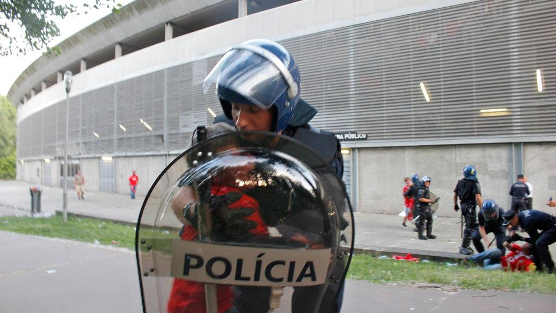 In this May 17 2015 file photo, a riot policeman holds a crying boy as his father is attacked by other policemen with batons, right, outside of a stadium, in Guimaraes, Portugal. Portugal's public prosecutor has filed charges Tuesday April 12, 2016, that could bring a prison sentence of more than 10 years against a policeman who beat a middle-aged football fan in front of his two young sons, with the video of the incident causing a national scandal. (AP Photo/Delfim Machado)