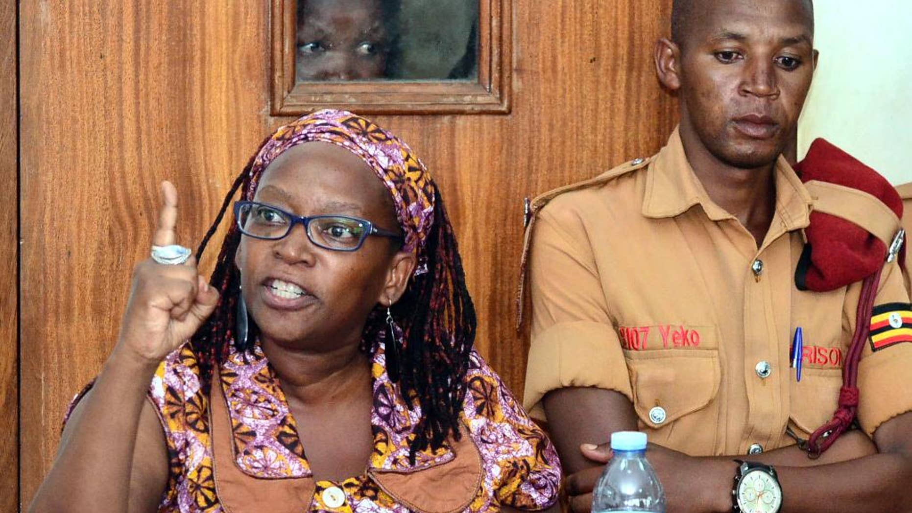 In this photo taken on Monday April 10, 2017, Makerere University researcher Dr Stella Nyanzi, left, gestures in the dock at Buganda Road Court in the capital Kampala, Uganda. A Ugandan academic detained for calling the country's president "a pair of buttocks" resisted attempts to forcibly carry out psychiatric tests on her, her attorney said Thursday, April 13 describing the alleged incident as an attack on her dignity.(AP Photo)