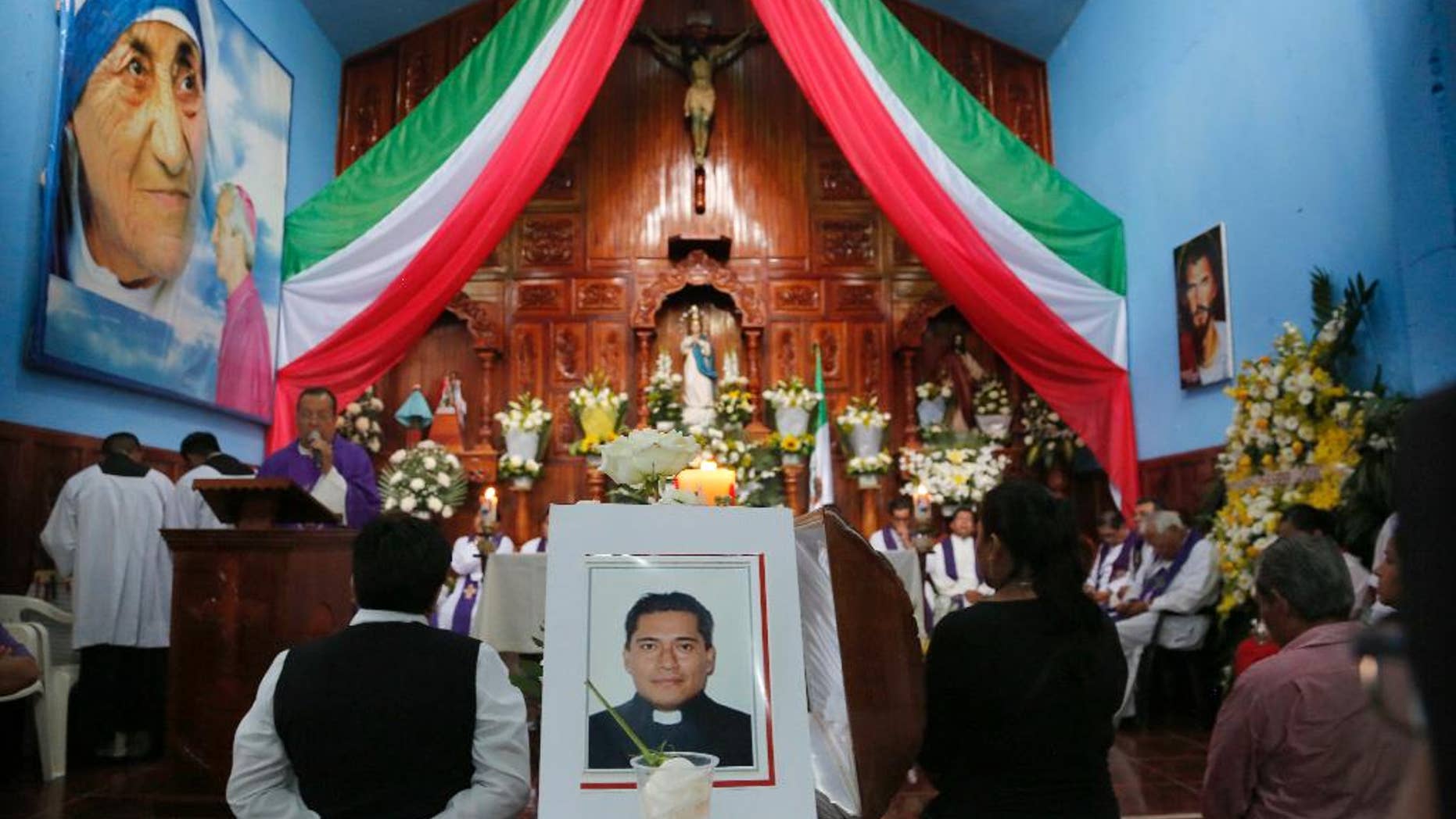 FILE - In this Sept. 21, 2016 file photo, people gather at Our Lady of Asuncion Church in Paso Blanco, Veracruz state, Mexico, for the funeral Mass of Rev. Jose Alfredo Suarez de la Cruz, one of two priests who was found bound and shot to death along a roadside on Sept. 19. Mexican authorities arrested a suspect in the abduction and murder of the two priests in Veracruz state last month. Mexico City prosecutors say in a statement released Monday, Oct. 17, 2016, that the unidentified person was detained Oct. 13 along with another person after they allegedly car-jacked a couple in the capital. (AP Photo/Marco Ugarte, File)
