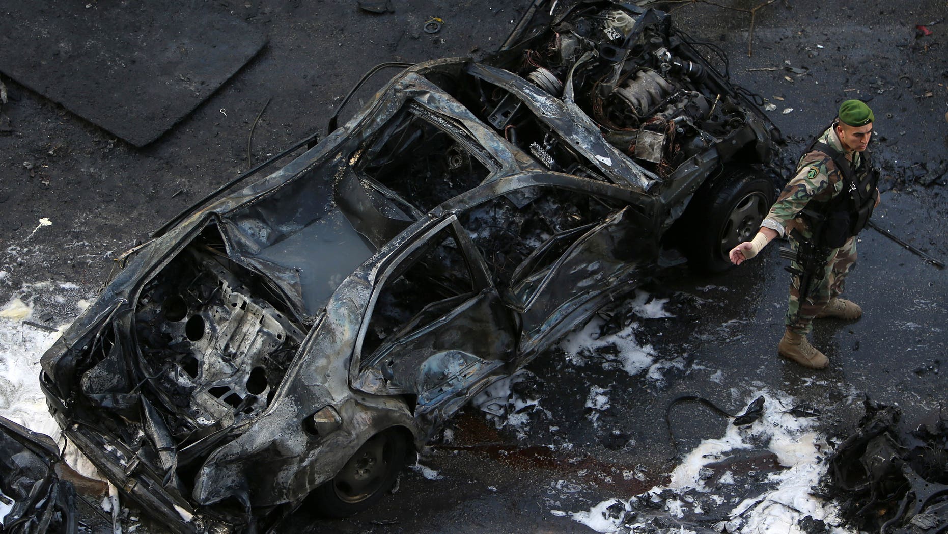 A Lebanese Army soldier stands next to a destroyed car at the scene of an explosion in central Beirut, Lebanon, Friday, Dec. 27, 2013. The state news agency said a bombing in central Beirut has killed several people, including Mohammed Chatah, a senior aide to former Lebanese Prime Minister Saad Hariri. (AP Photo/Hussein Malla)