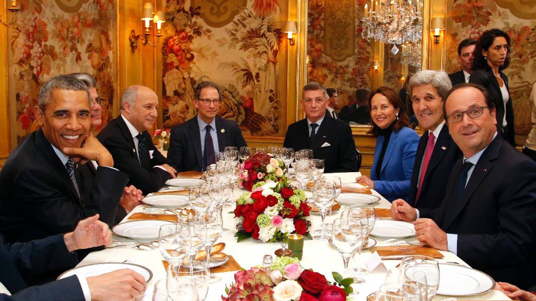 President Barack Obama, left, sits with French President Francois Hollande, right, as they have dinner at the Ambroisie restaurant in Paris, France, with Secretary of State John Kerry, 2nd right, French Minister for Ecology, Sustainable Development and Energy Segolene Royal, 3rd right, and French Foreign Minister, Laurent Fabius, 3rd left, Monday, Nov. 30, 2015. Obama is in France for a two-day visit as part of the COP21, the United Nations Climate Change conference. Other officials are : Translator, Thomas Ronkin, 2nd left, Charles Kupchan, top left, and French President Hollande's Military Chief of Staff General Benoit Puga, top right. (AP Photo/Thibault Camus, Pool)