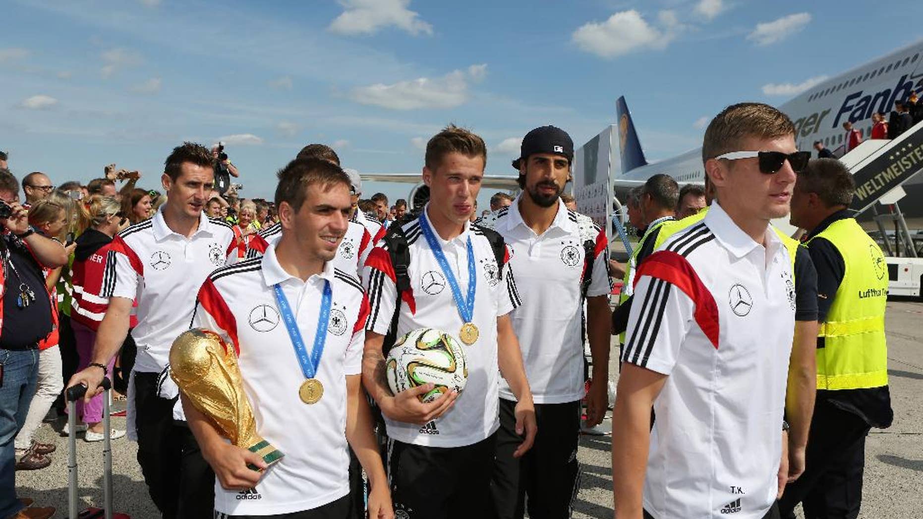 German national soccer players from left : Miroslav Klose, Philipp Lahm, Lars Bender, Sami Khedira and Toni Kroos arrive with the team at Tegel airport in Berlin Tuesday July 15, 2014. Germany beat Argentina 1-0 on Sunday to win its fourth World Cup title. (AP Photo/Karina Hessland,pool)