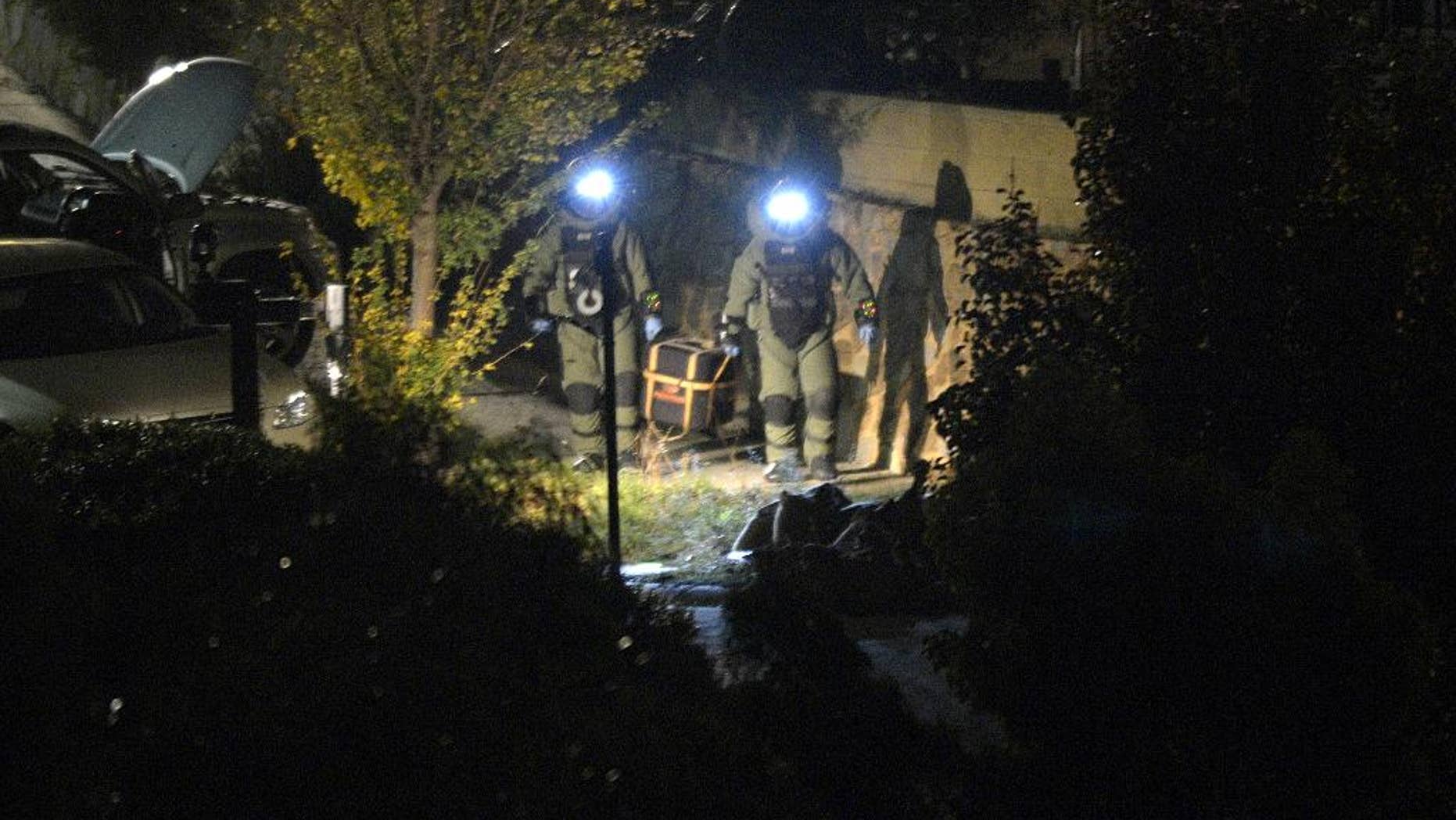 In this May 8, 2015 photo, two members of the police bomb squad carry a device to a sand bagged area to be detonated as terror raids are carried out at Greenvale in Melbourne, Australia. A 17-year-old boy arrested last week when police allegedly found three homemade bombs in his family home in Australia's second-largest city appeared in a children's court on Monday, May 11, 2015, charged with terrorism offenses. (Tracey Nearmy/AAP Image via AP) NO ARCHIVING. AUSTRALIA OUT, NEW ZEALAND OUT, PAPUA NEW GUINEA OUT, SOUTH PACIFIC OUT