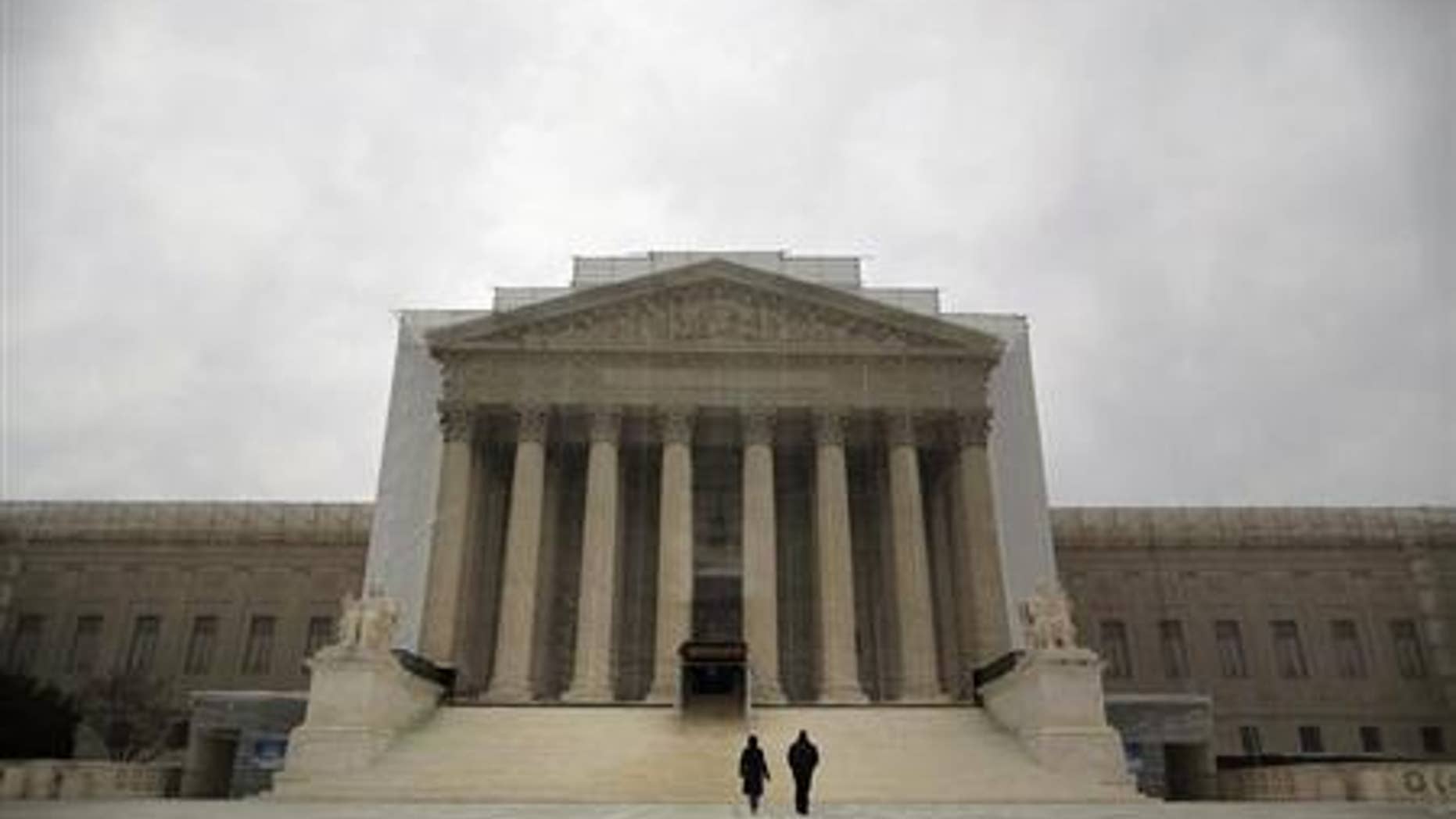 People walk in front of the Supreme Court building in Washington, March 24, 2013. REUTERS/Jonathan Ernst