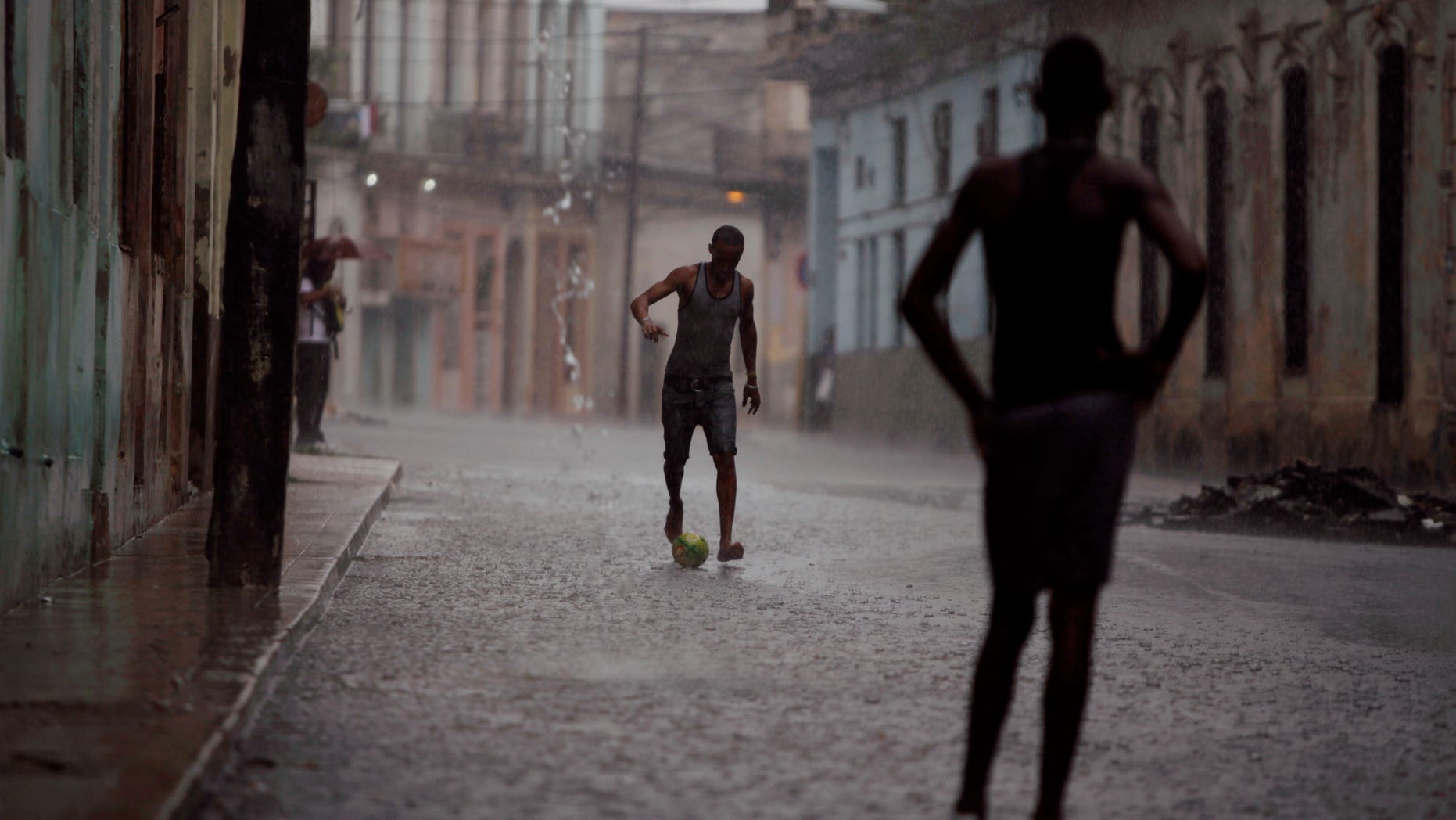 Two young men kick a soccer ball around in the rain on a flooded street in Havana, Cuba, Friday Sept.2, 2011.(AP Photo/Javier Galeano)