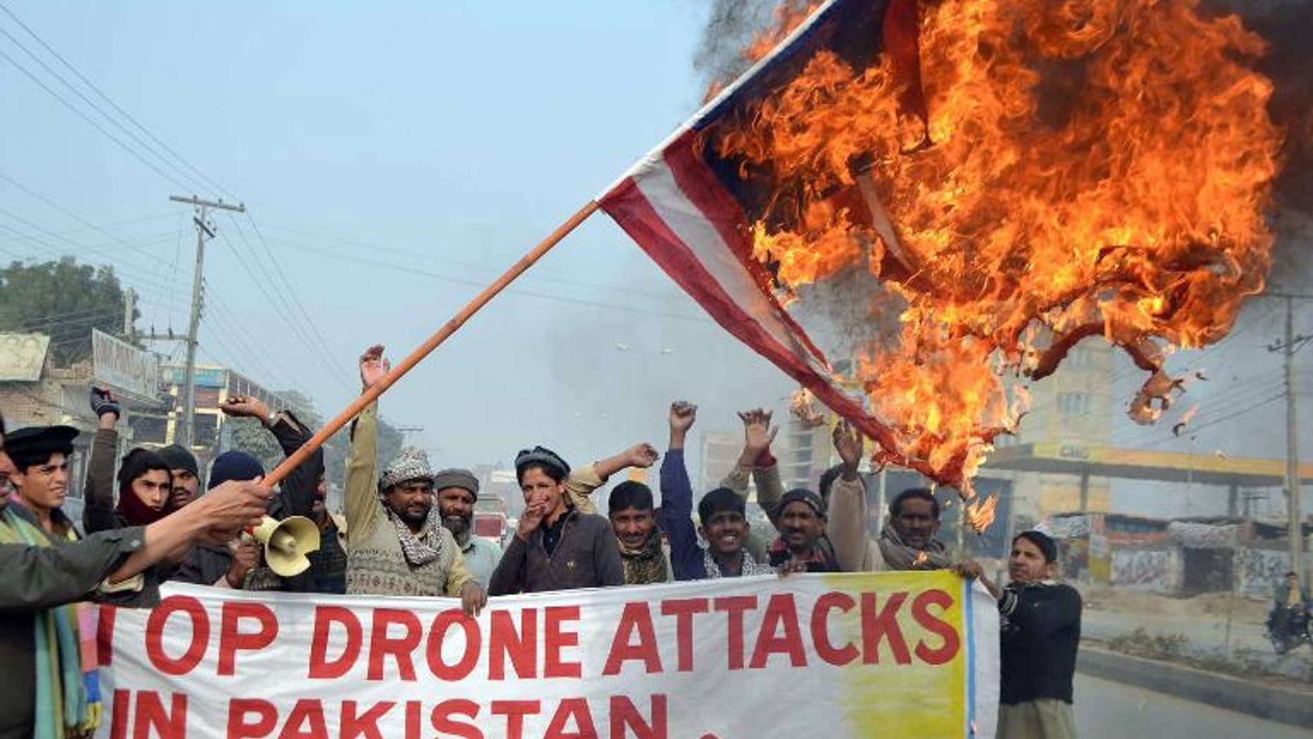 A Pakistani demonstrator holds a burning US flag during a protest in Multan against drone attacks in tribal areas, on January 8, 2013