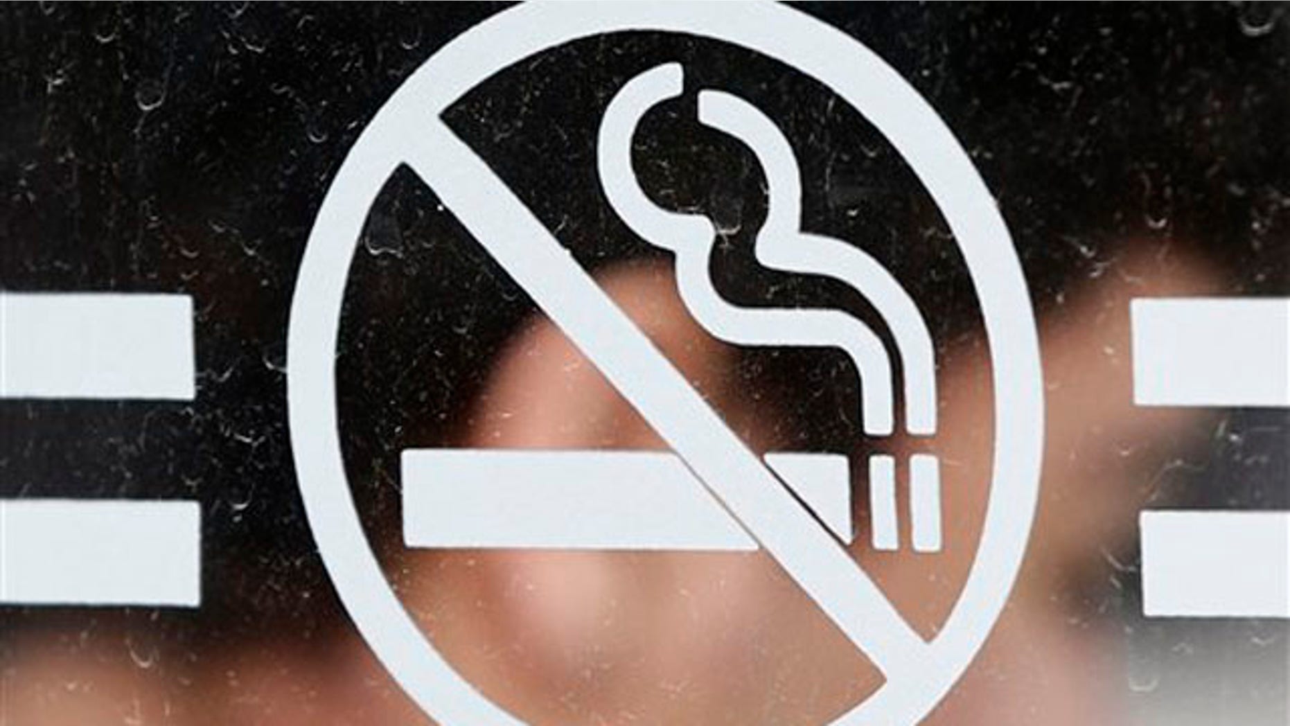 A student waits for a bus behind a no smoking sign at the State University of New York at Albany in Albany, N.Y., on Tuesday, June 26, 2012. Tobacco use bans are sweeping campuses nationwide. (AP Photo/Mike Groll)