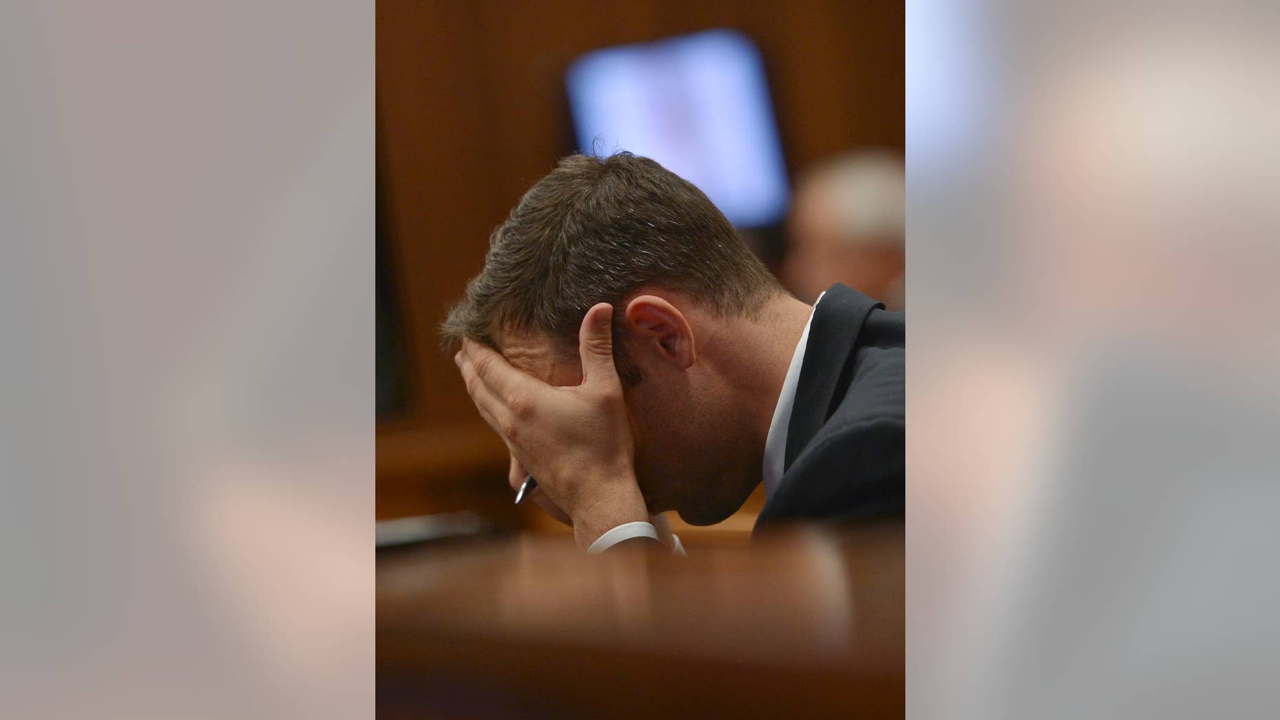 March 12, 2014: Oscar Pistorius cradles his head in his hands as he listens to cross questioning about the events surrounding the shooting death of his girlfriend Reeva Steenkamp, in court during the second week of his trial in Pretoria, South Africa.