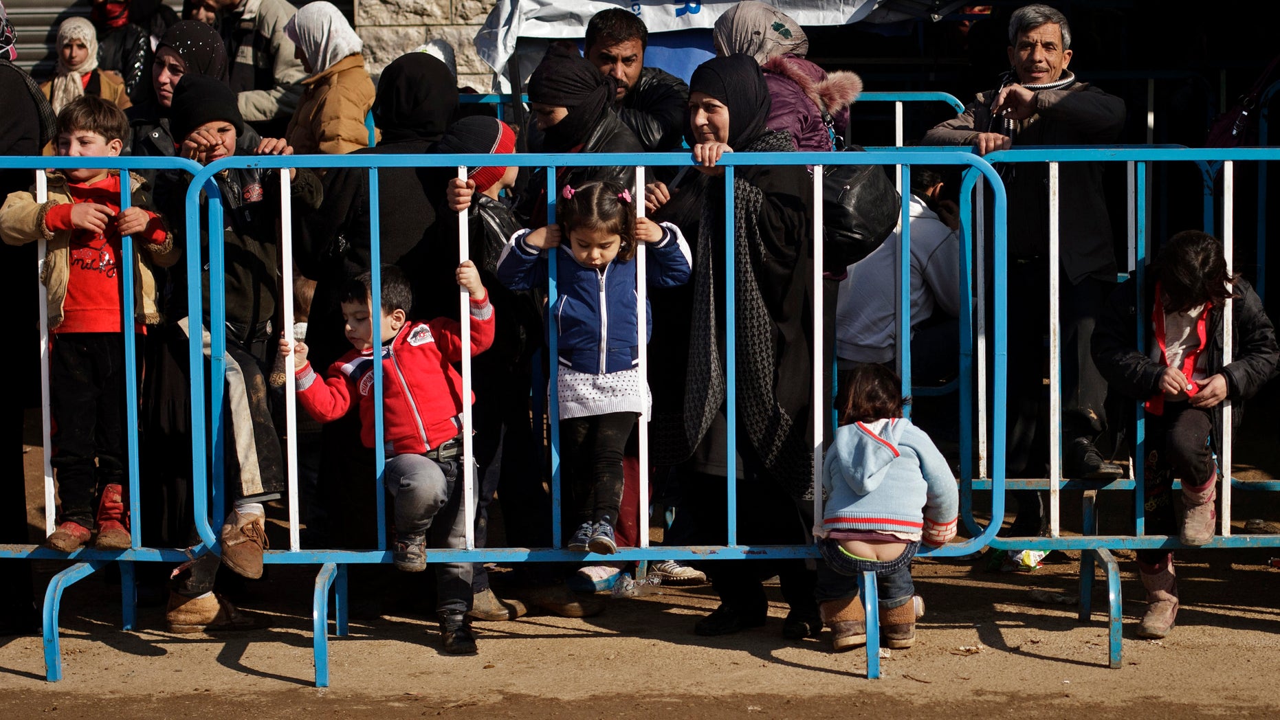 This Wednesday, Dec. 18, 2013 photo shows Syrian children passing time while waiting with their families at the U.N. refugee agency's registration center in Zahleh, in Lebanon's Bekaa Valley. With an endless surge of refugees now fighting the bitter winter cold, humanitarian organizations are struggling to find new ways to reach refugees with the timely, accurate information they need to survive, including the recruitment of refugees as volunteers so that people can access information from sources they can trust.(AP Photo/Maya Alleruzzo)