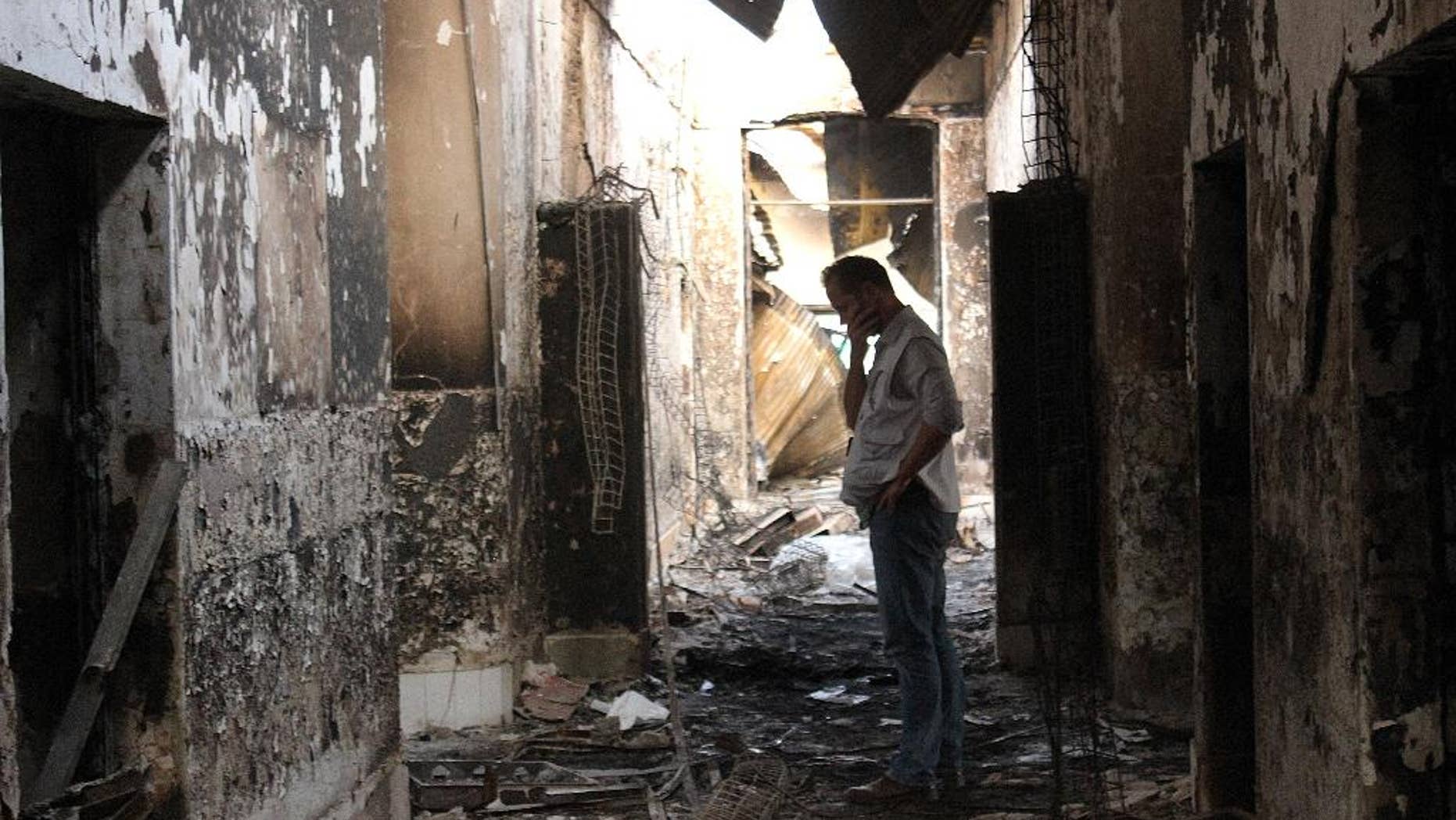 FILE - In this Friday, Oct. 16, 2015, file photo, an employee of Doctors Without Borders walks inside the charred remains of their hospital after it was hit by a U.S. airstrike in Kunduz, Afghanistan. An investigative report on the U.S. air attack that killed more than two dozen civilians at a medical charity's hospital in northern Afghanistan last month says the crew of the attacking plane misidentified the target, believing it to be a government compound taken over by the Taliban. (Najim Rahim via AP)
