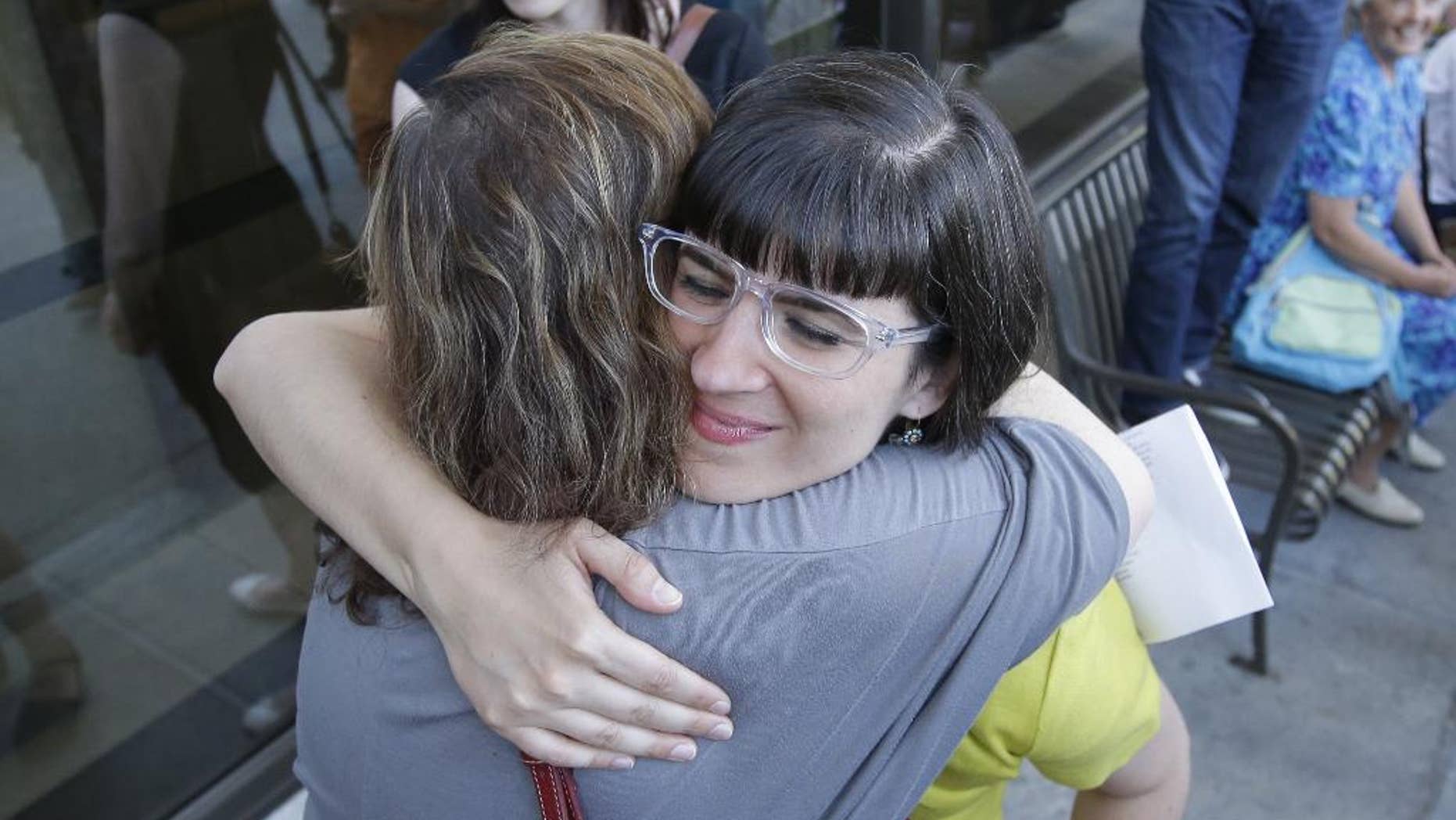 Kate Kelly receives a hug from a supporter after walking to the Church Office Building of the Church of Jesus Christ of Latter-day Saints Sunday, June 22, 2014, in Salt Lake City. While Kelly's former church leaders meet in Virginia on Sunday night to decide if she'll be ousted from her church, the founder of a prominent Mormon women's group will hold a vigil in Salt Lake City along with hundreds of her supporters. The leader of Ordain Women is accused of apostasy, defined as repeated and public advocacy of positions that oppose church teachings. (AP Photo/Rick Bowmer)