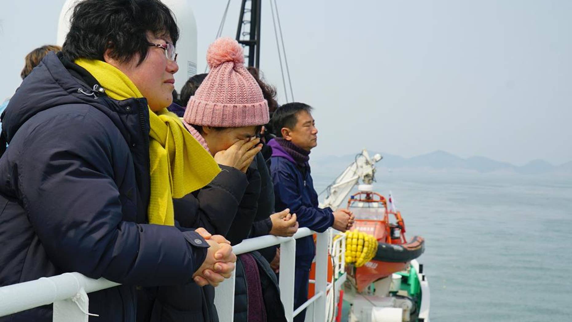 In this photo provided by South Korean ministry of Oceans and Fisheries, relatives of the missing victims wipe tears as they attend religious services in waters off Jindo, South Korea, Tuesday, March 28, 2017. South Korean salvage crews on Tuesday found what is presumed to be the remains of one of the missing victims of a 2014 ferry disaster that killed 304 people, an official said. (South Korean Ministry of Oceans and Fisheries via AP)