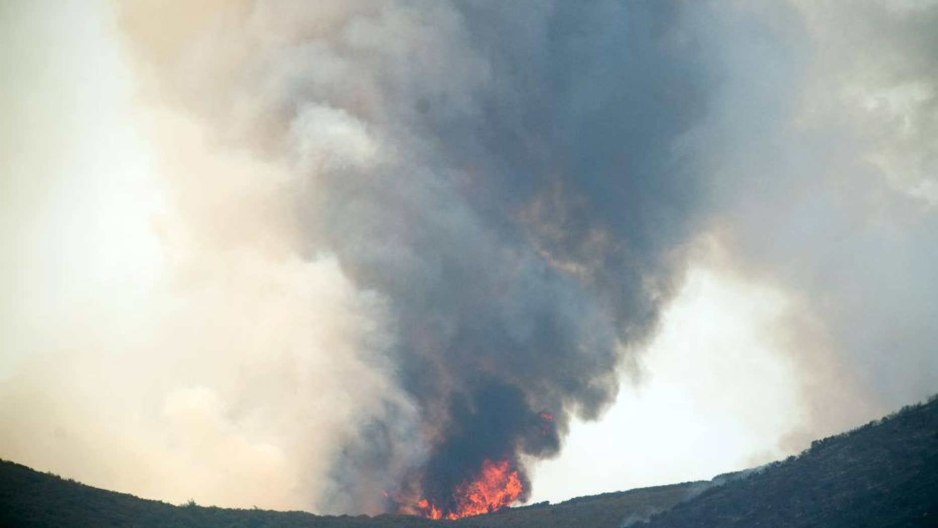 Smoke and flames rise from a ridge top as the Wragg fire burns near Winters, Calif., on Thursday, July 23, 2015. According to Cal Fire, the blaze scorched more than 6,000 acres and is threatening 200 structures. (AP Photo/Noah Berger)