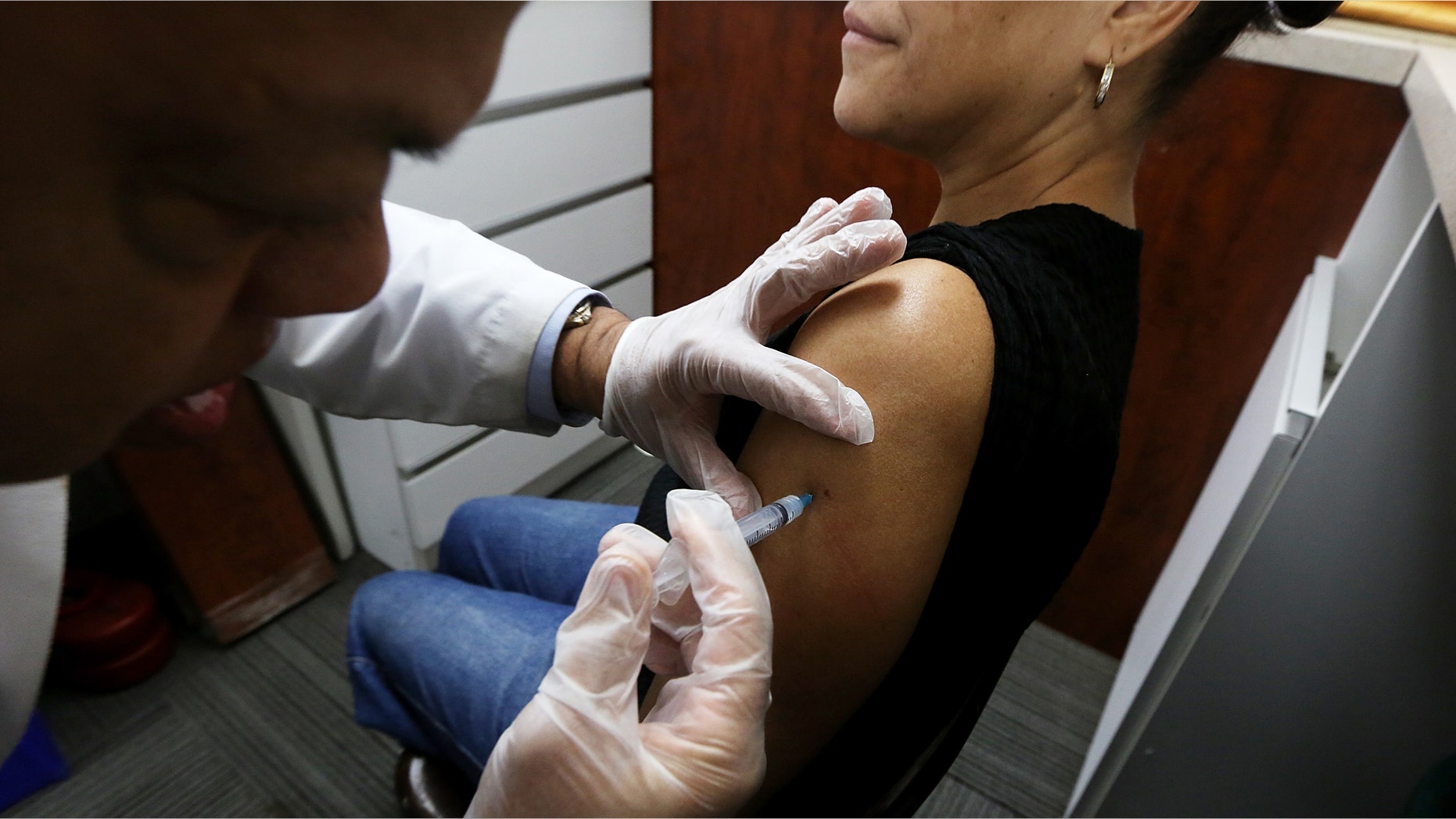 NEW YORK, NY - JANUARY 14: Phamacist Prakash Deshpande injects a patient with influenza vaccine at a Manhattan pharmacy on January 14, 2013 in New York City. The state of New York has declared a public health emergency in a flu epidemic of more than 19,000 confirmed cases in the state. (Photo by Mario Tama/Getty Images)