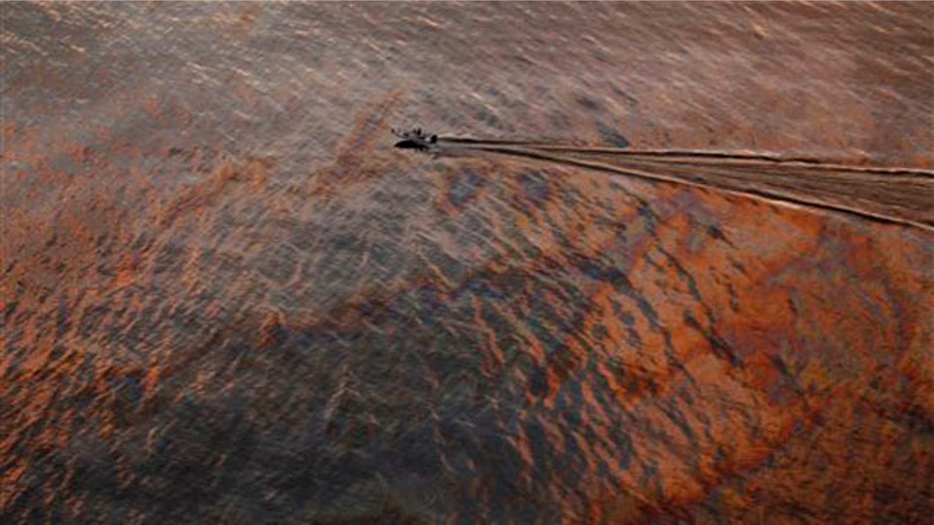 In this July 31 file photo, a boat motors through an oil sheen from the Deepwater Horizon oil spill off the Louisiana coast.