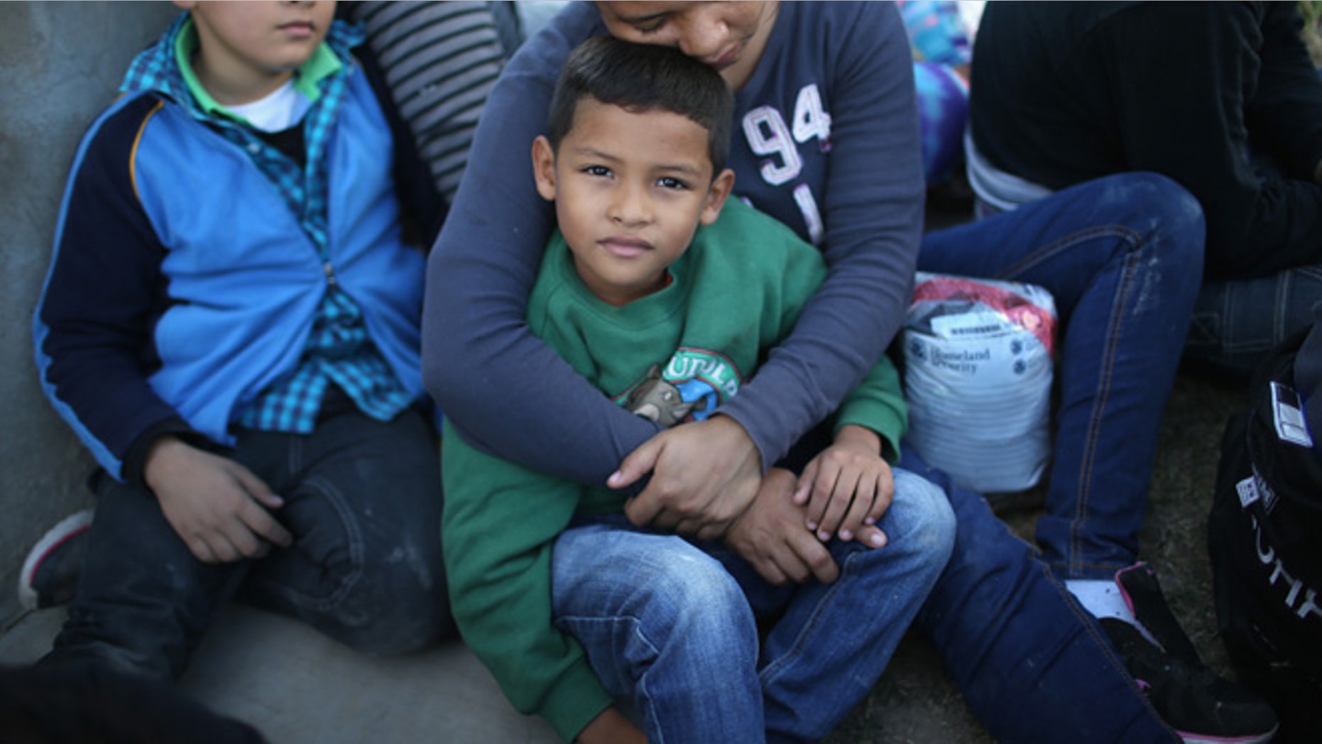 RIO GRANDE CITY, TX - DECEMBER 08: A Honduran mother holds her son, 7, after she turned her family in to U.S. Border Patrol agents on December 8, 2015 near Rio Grande City, Texas. They had just illegally crossed the U.S.-Mexico border into Texas. She said she brought her two daughters to escape violence in the Central American country. The number of migrant families and unaccompanied minors has again surged in recent months, even as the total number of illegal crossings nationwide has gone down over the previous year. (Photo by John Moore/Getty Images)