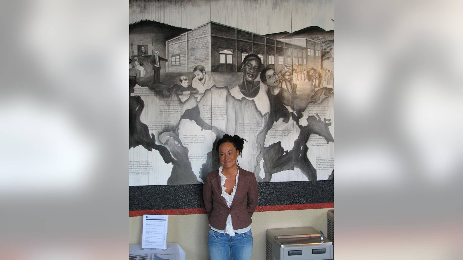 FILE - In this July 24, 2009, file photo, Rachel Dolezal, a leader of the Human Rights Education Institute, stands in front of a mural she painted at the institute's offices in Coeur d'Alene, Idaho. Dolezal, now president of the Spokane, Wash., chapter of the NAACP, is facing questions about whether she lied about her racial identity, with her family saying she is white but has portrayed herself as black. (AP Photo/Nicholas K. Geranios, File)