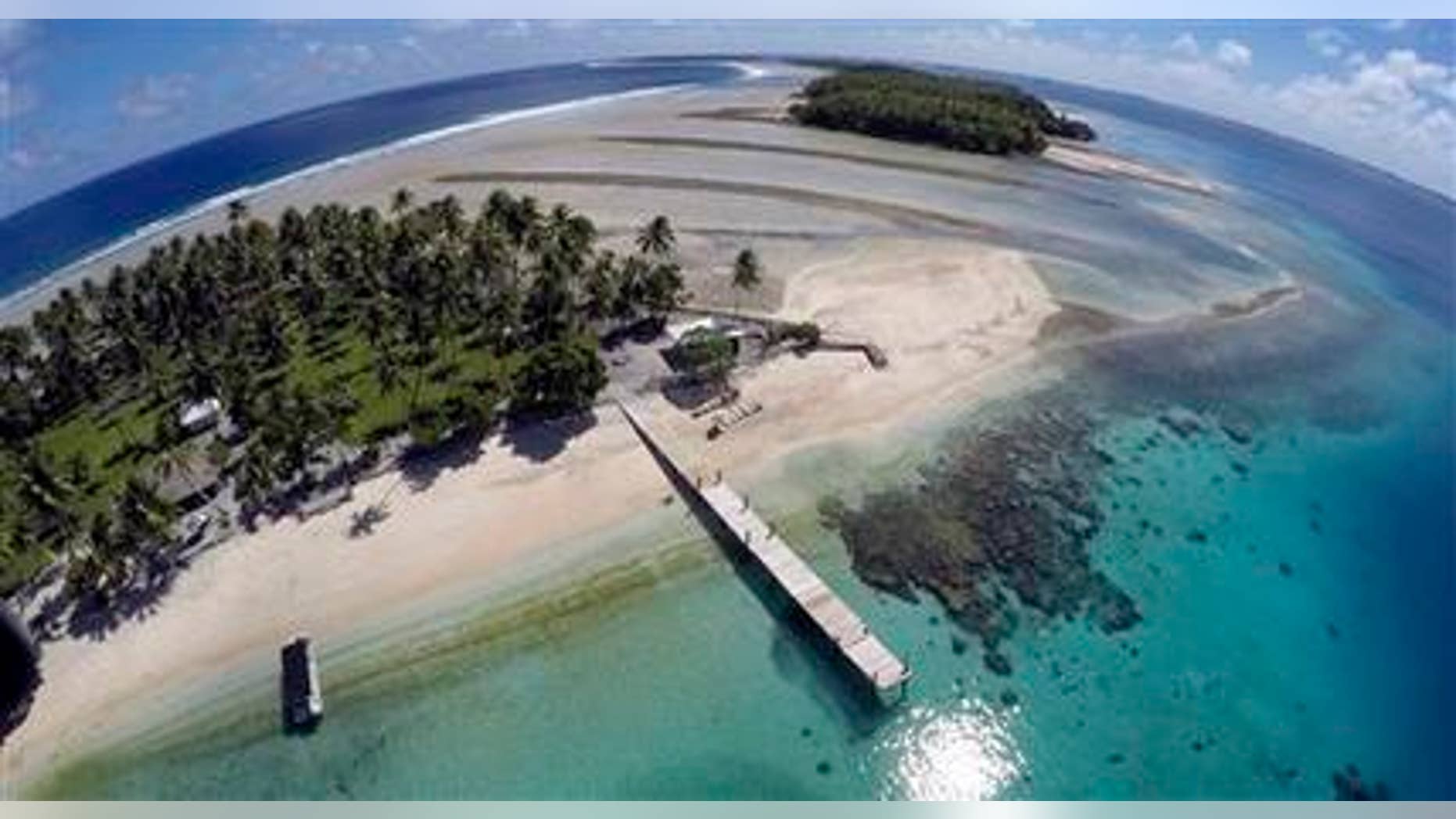 This Nov. 8, 2015 aerial photo shows a small section of the atoll that has slipped beneath the water line only showing a small pile of rocks at low tide on Majuro Atoll in the Marshall Islands. Climate change poses an existential threat to places like the Marshall Islands, which protrude only 6 feet (2 meters) above sea level in most places. (AP Photo/Rob Griffith)