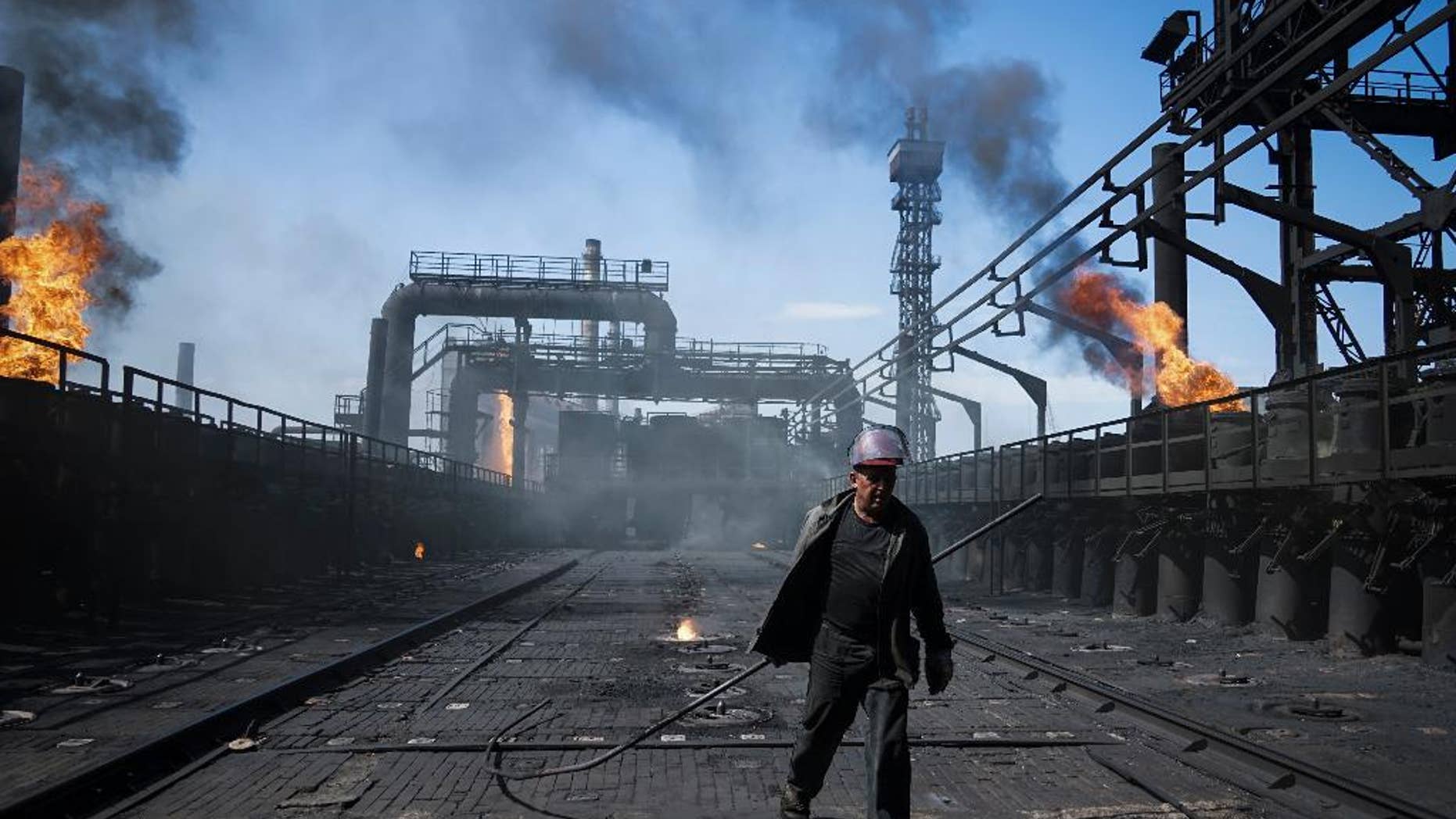 A worker carries a metal rod at the front-line Avdivka coking plant in eastern Ukraine, where the power cut out after shelling.