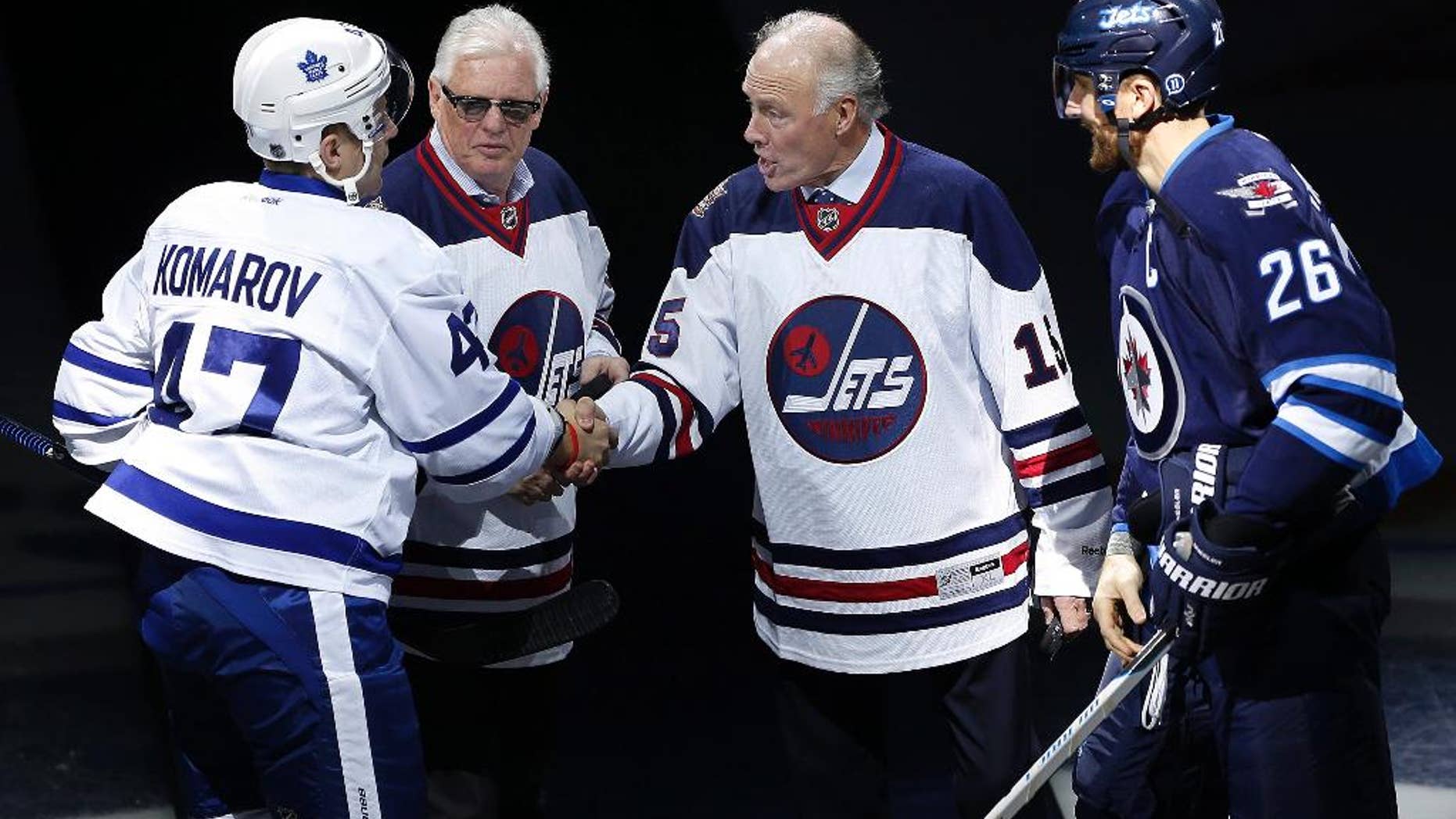 Former Winnipeg Jets' Anders Hedberg, second from right, shakes hands with Toronto Maple Leafs' Leo Komarov (47) as Ulf Nilsson and Winnipeg Jets' Blake Wheeler (26) watch during the induction ceremony for the Winnipeg Jets Hall of Fame in Winnipeg, Manitoba, on Wednesday, Oct. 19, 2016. Bobby Hull was also inducted but did not attend. (John Woods/The Canadian Press via AP)