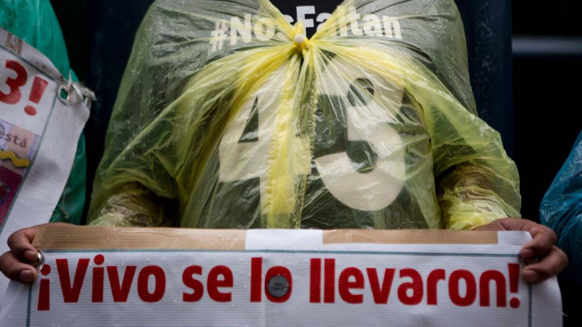 FILE - In this May 26, 2016, file photo, a relative carries signs that reads in Spanish "They took them alive!" referring to the 43 missing students from a rural teachers college during a march in Mexico City, Thursday. Mexico's National Human Rights Commission said Monday, July 11, that a classmate of 43 college students who disappeared in 2014 had been tortured before his body was found the following day. (AP Photo/Eduardo Verdugo, File)