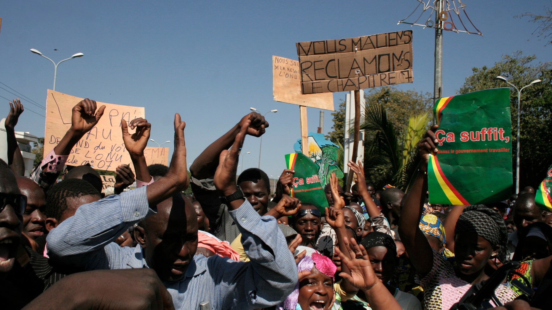 FILE - In this Dec. 8, 2012, file photo, Malians demonstrate in favor of an international military intervention to regain control of the country's Islamist-controlled north, in Bamako, Mali. They carry signs that say 'That's enough, let the government work' right, and 'We Malians Demand Chapter 7,' center, referring to the chapter of the United Nations Charter which would be used to authorize international military intervention. The United States has its hands tied in confronting an uptick of threats from North Africa, the world’s newest jihadist hotspot. The spread of al-Qaida-linked militants across Libya, Algeria and Mali reflects a rise in local extremists who have been emboldened since the attack last Sept. 11 on a U.S. diplomatic post in Benghazi, (AP Photo/Harouna Traore)