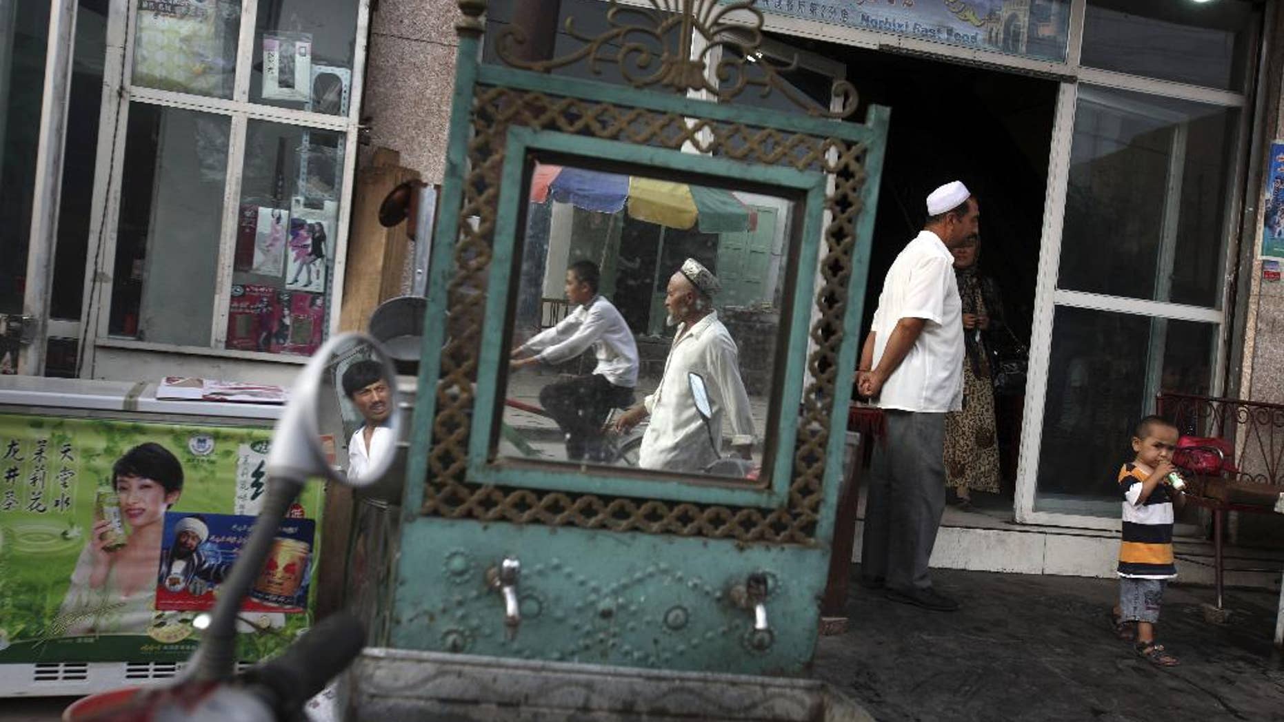 FILE - In this Aug. 6, 2008, file photo, Uighurs are seen outside a restaurant in Kashgar in China's western Xinjiang province. Since 2015 militants belonging to the Uighur ethnic group native to the vast Xinjiang region in western China have shown signs of becoming a force in Islamic extremism globally, a development that is reshaping both the ground war in Syria and Chinese foreign policy. (AP Photo/Ng Han Guan, File)