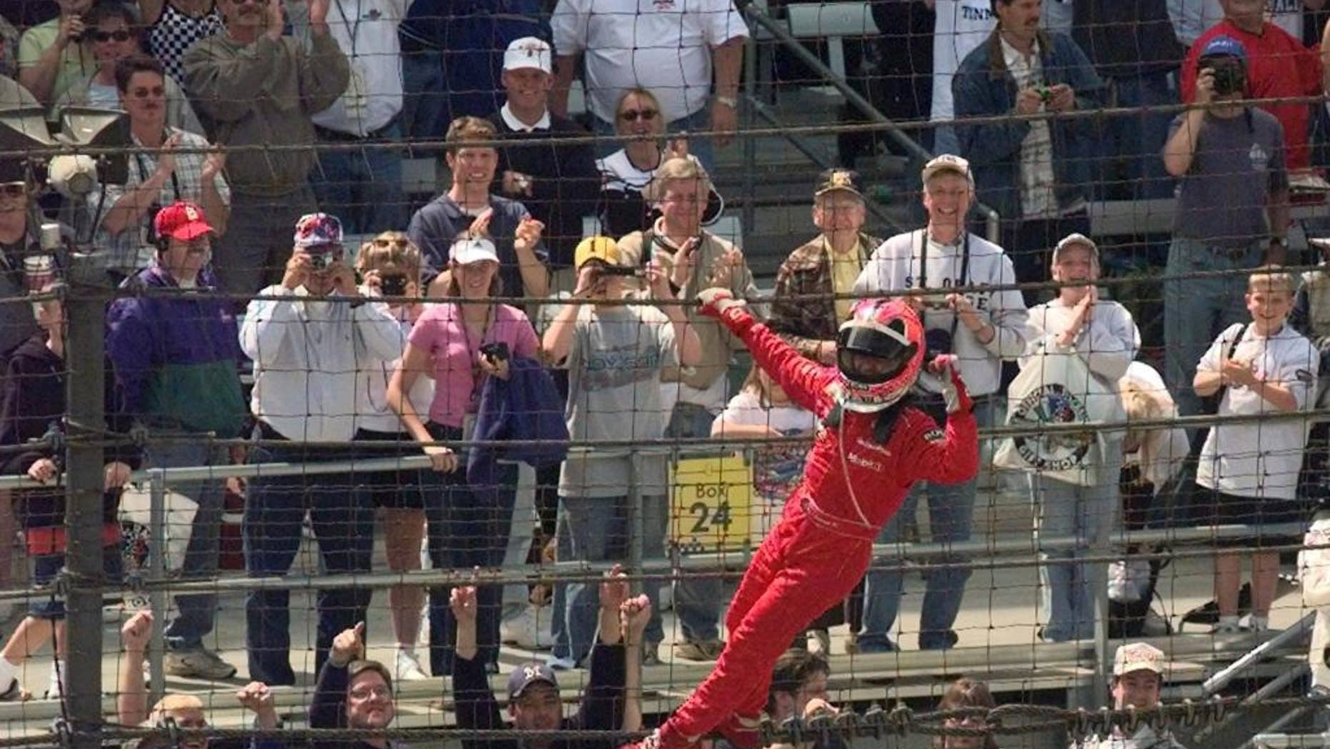 FILE - In this May 27, 2001, file photo, Helio Castroneves, of Brazil, celebrates after winning the 85th running of the Indianapolis 500 auto race by climbing the fencing near the start-finish line at Indianapolis Motor Speedway. (AP Photo/Dave Parker, File)