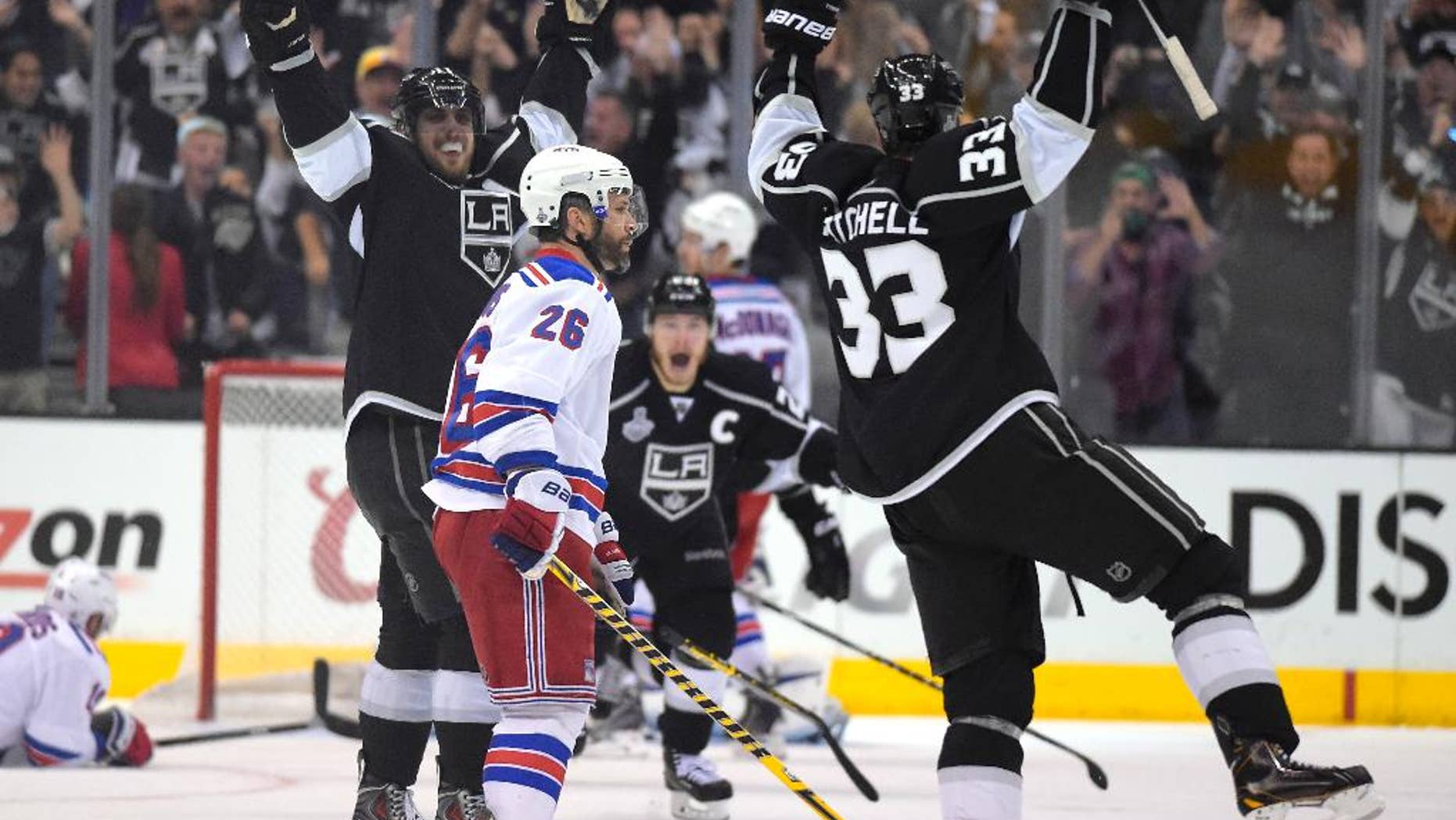 Los Angeles Kings right wing Dustin Brown, center, celebrates after scoring the game-winning goal, along with center Anze Kopitar, second from left, of Slovenia, and defenseman Willie Mitchell, right, as New York Rangers center Brad Richards, left, lies on the ice and Martin St. Louis (26) watches during the second overtime period in Game 2 of the NHL hockey Stanley Cup Finals, Saturday, June 7, 2014, in Los Angeles. The Kings won 5-4. (AP Photo/Mark J. Terrill)