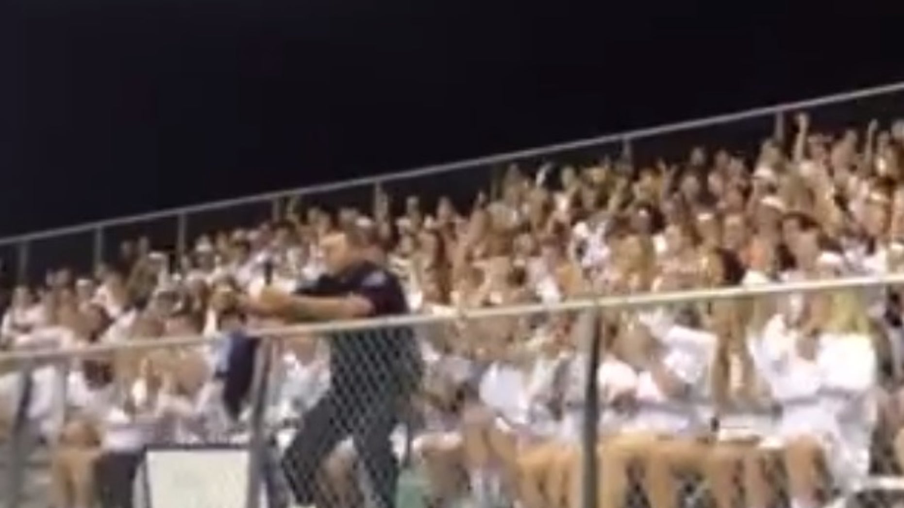 Officer Jack Taschner leads a cheer at a high school football game.