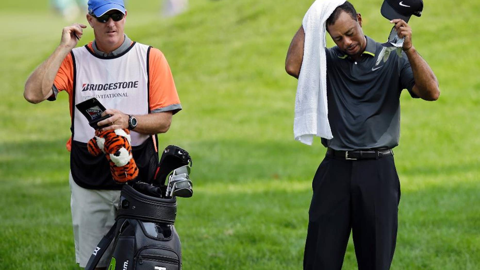 Tiger Woods wipes his head as he waits to hit to the 10th green with caddie Joe Lacava, left, during the second round of the Bridgestone Invitational golf tournament Friday, Aug. 1, 2014, at Firestone Country Club in Akron, Ohio. (AP Photo/Mark Duncan)