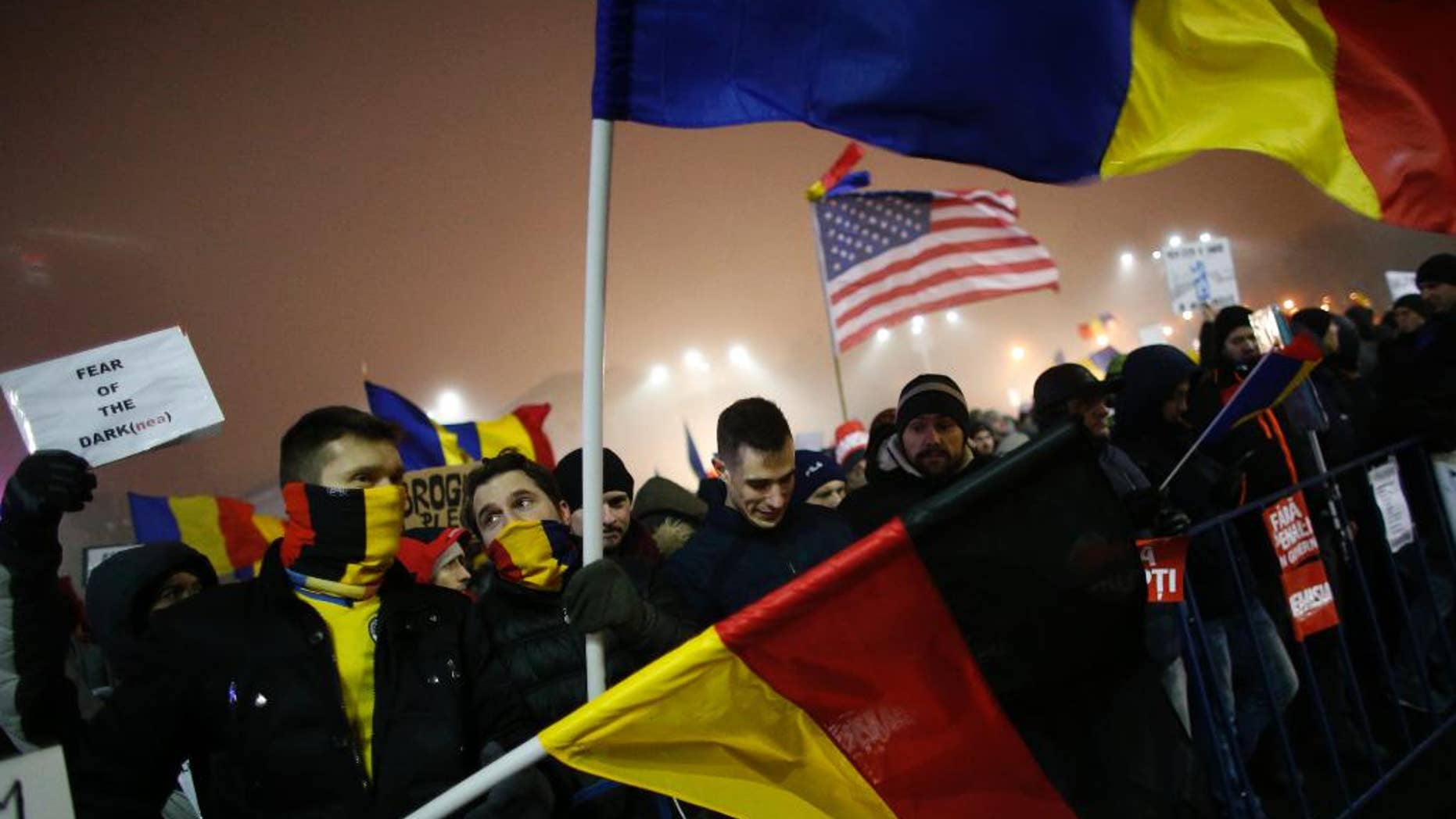 Protesters wave U.S., German and Romanian flags during a protest in Bucharest, Romania, Monday, Feb. 6, 2017. The leader of Romania's ruling center-left coalition said Monday the government won't resign following the biggest demonstrations since the end of communism against a measure that would ease up on corruption. (AP Photo/Darko Bandic)