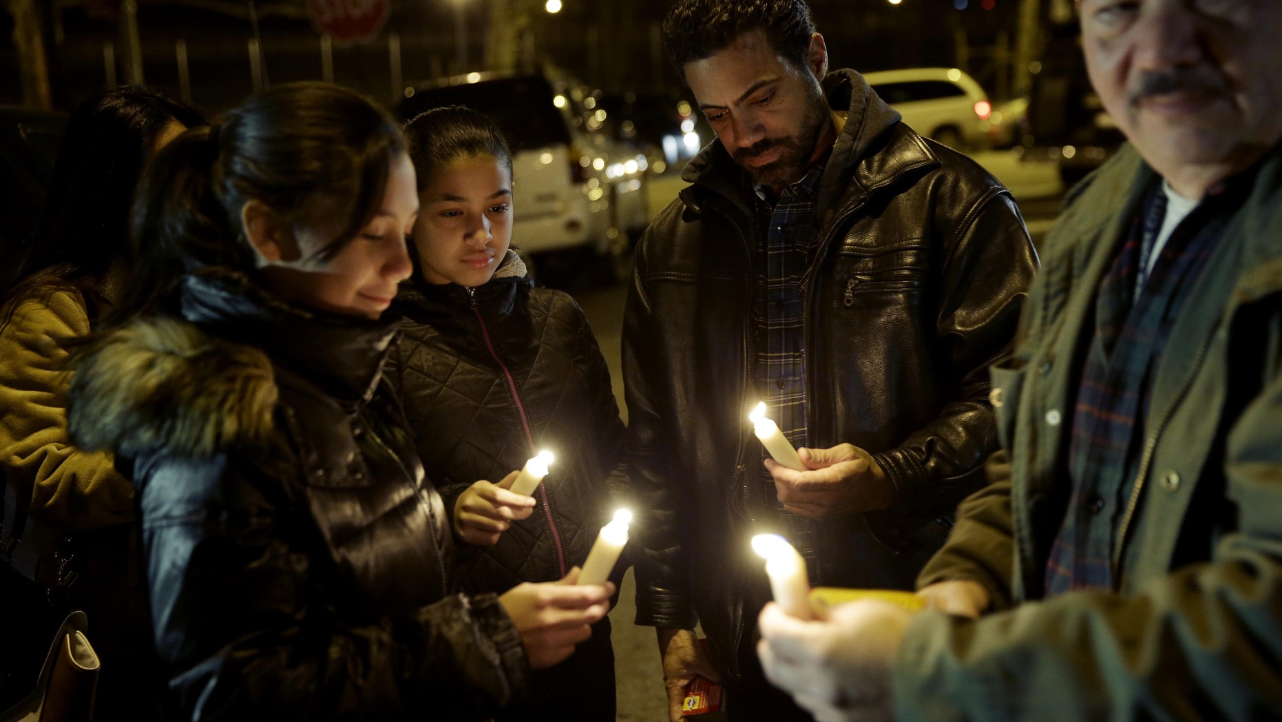 People light candles with members of Rafael Ramos' family in Brooklyn, New York, Sunday, Dec. 21, 2014.