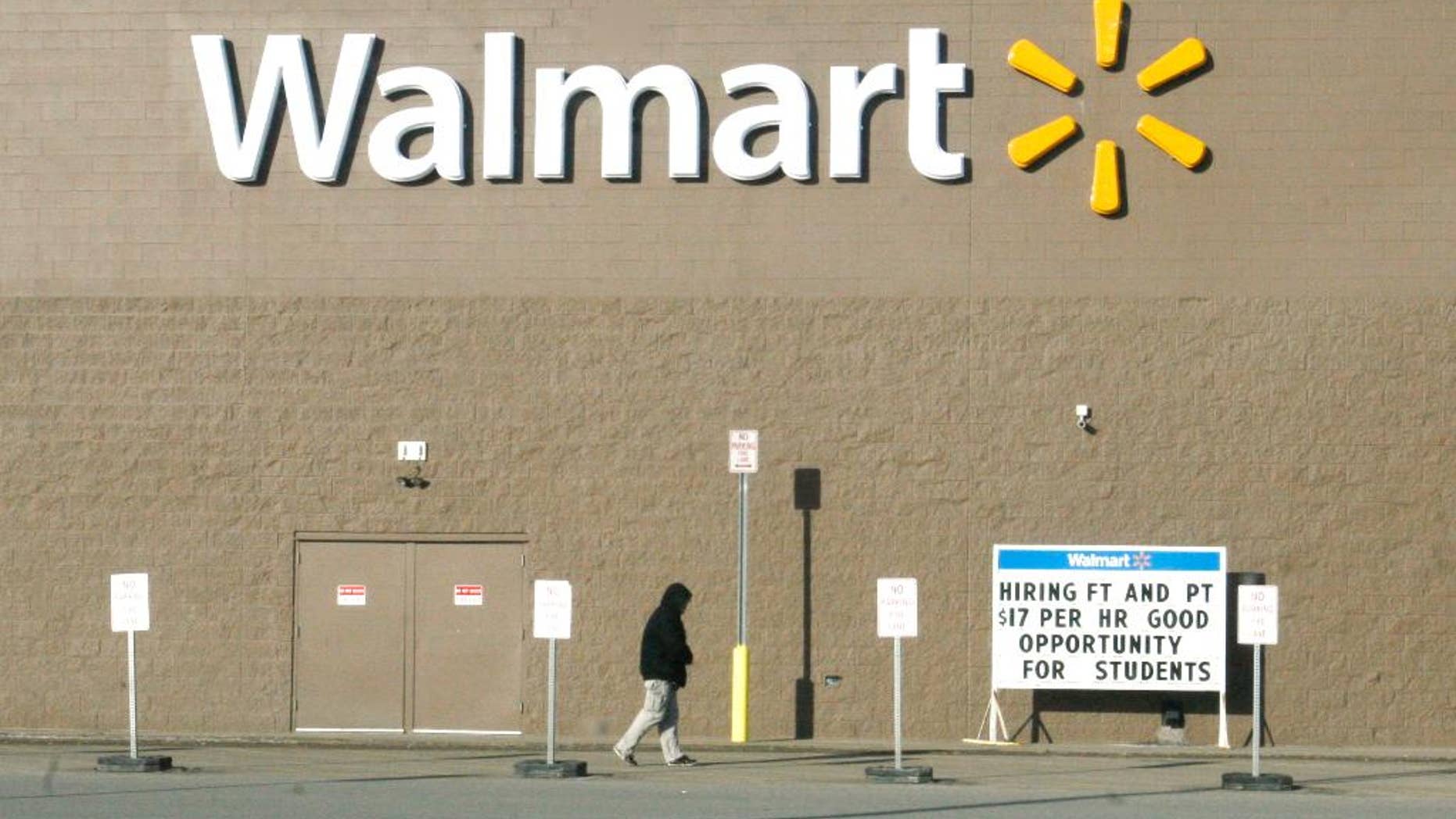 ADVANCE FOR USE SUNDAY, APRIL 13, 2014 AND THEREAFTER - A shopper walks next to a Walmart store on Friday, Feb. 28, 2014 in Williston, N.D. near a sign advertising a $17 hourly wage for new employees - a rate higher than in many cities. The Bakken shale fields oil boom has brought about a high cost of living in the area, especially for housing. (AP Photo/Martha Irvine)