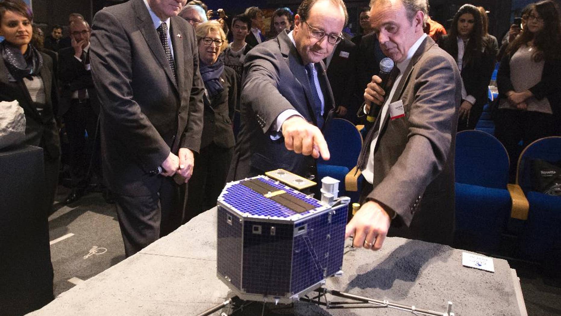 FILE - In this Wednesday, Nov. 12, 2014 file photo, French President Francois Hollande, center, with French astrophysicist Francis Rocard look at a model of Rosetta lander Philae, as they visit the Cite des Sciences at La Villette in Paris during a broadcast of the Rosetta mission as it orbits around comet 67/P Churyumov-Gersimenko. The European Space Agency says Wednesday July 27, 20167 it is switching off its radio link to the probe that landed on a comet, after receiving no signal from the lander for a year. (AP Photo/Jacques Brinon, Pool, file)